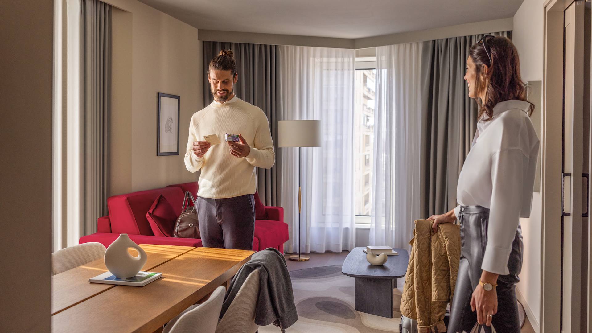 Hombre y mujer de pie en habitación con lámpara y mesa