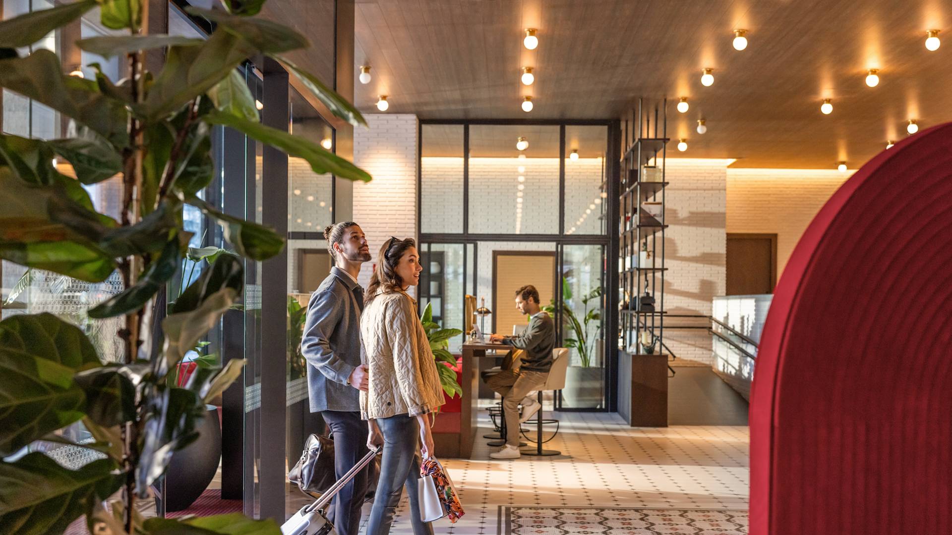 Man and woman walking through main entrance into lobby with luggage