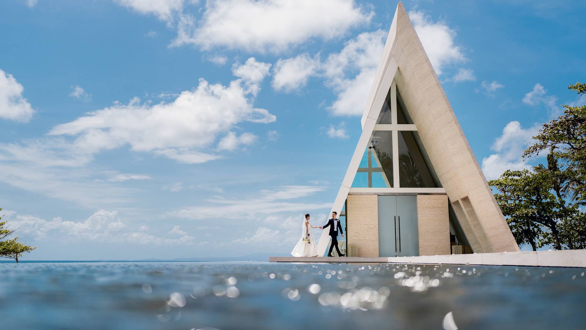 Una pareja el día de su boda camina por un lugar con vista a la piscina para celebrar su boda