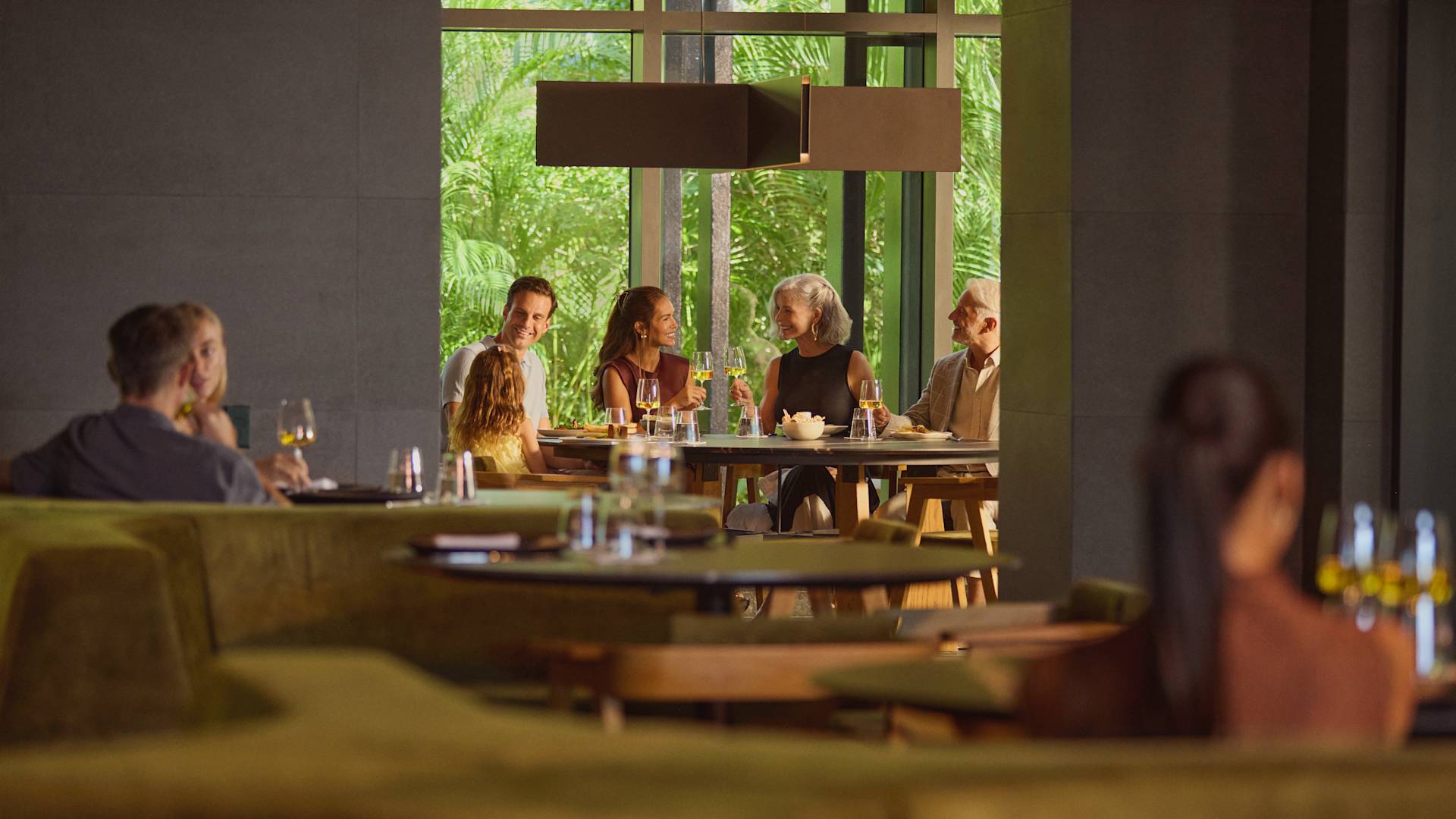 ホテルのレストランで食事を楽しむ祖父、祖母、父、母、娘の家族