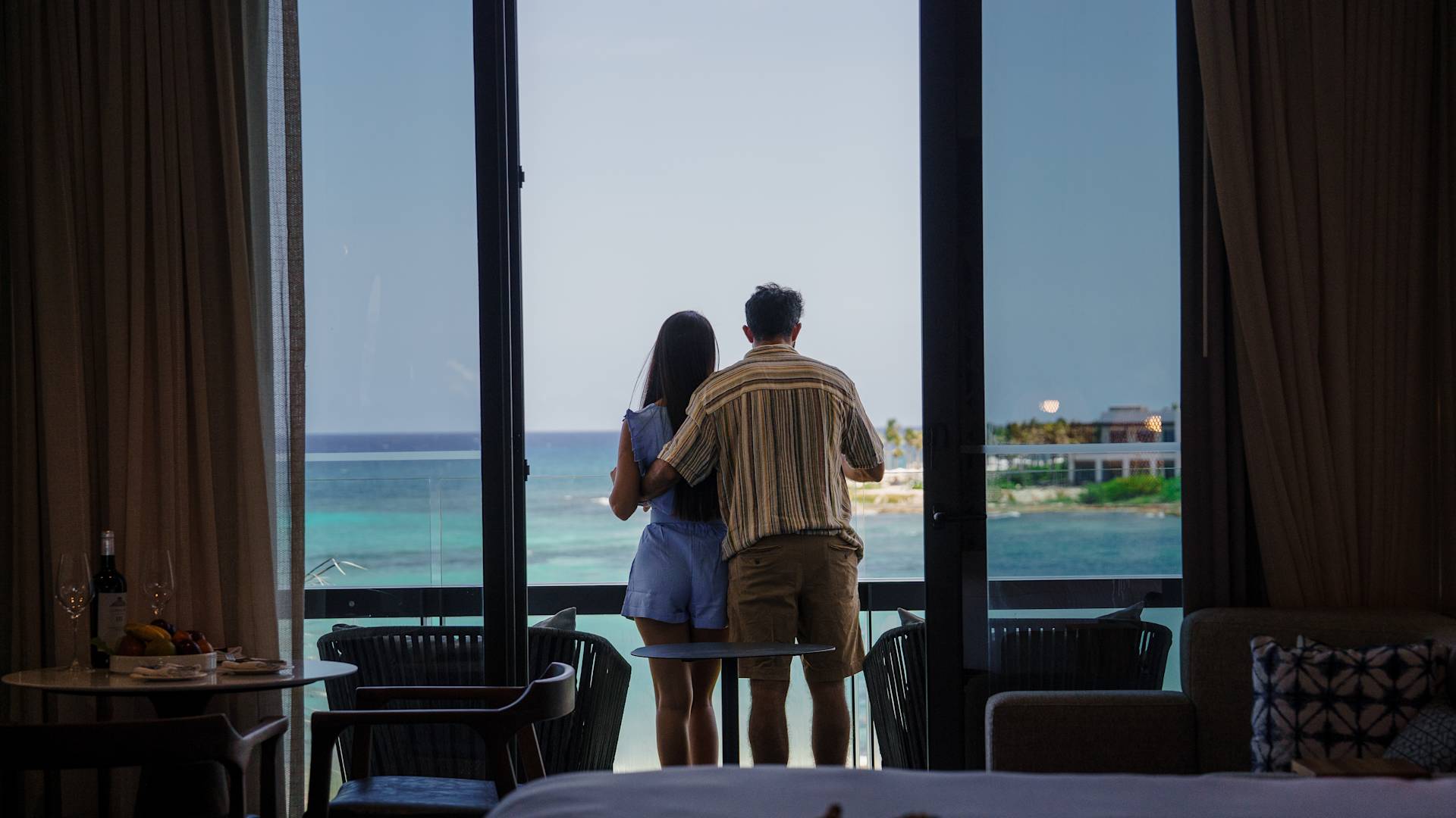 Pár stojí na balkóně zezadu a dívá se na výhled na oceán