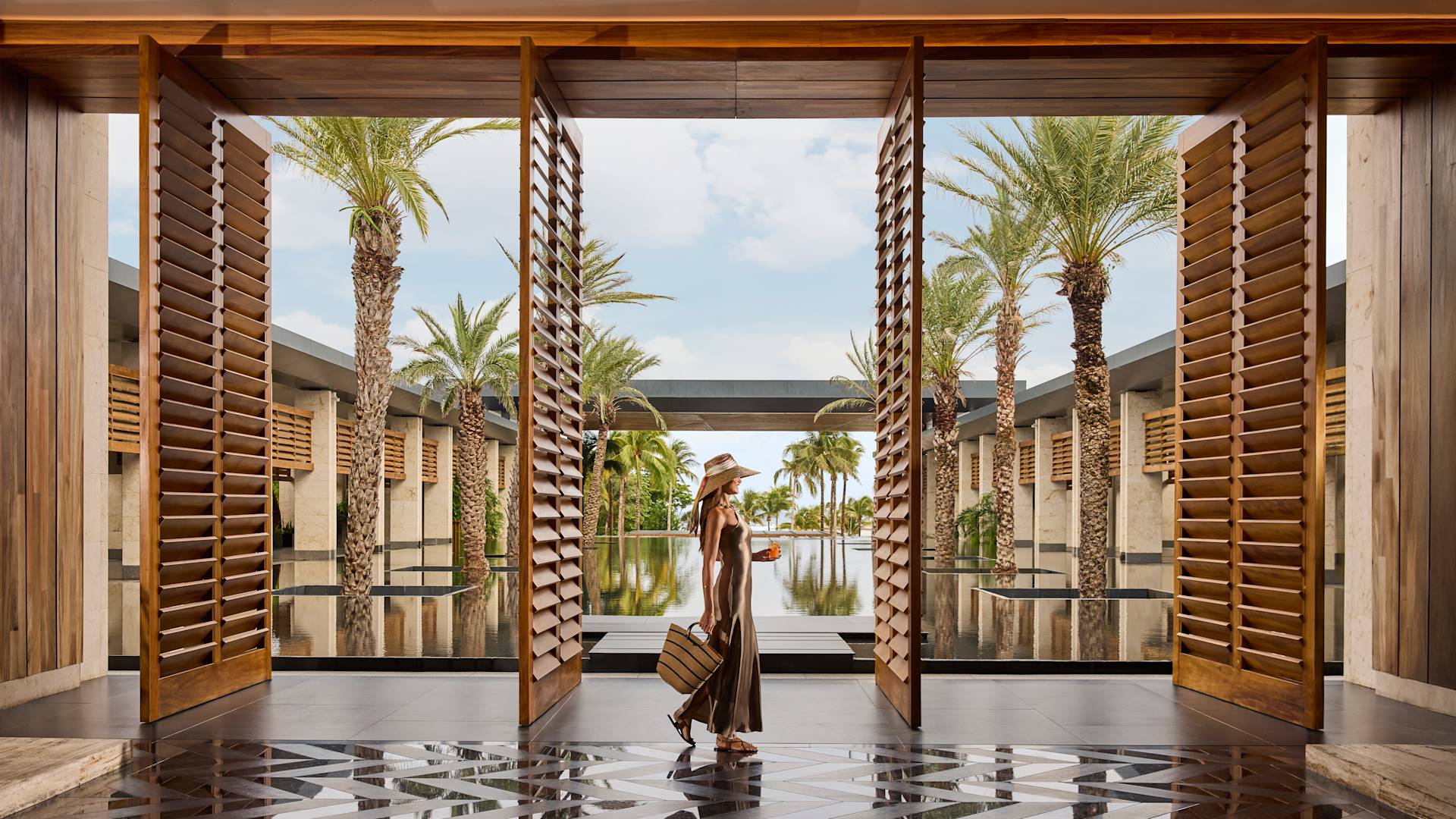 Woman walking through lobby past hotel entrance with luggage