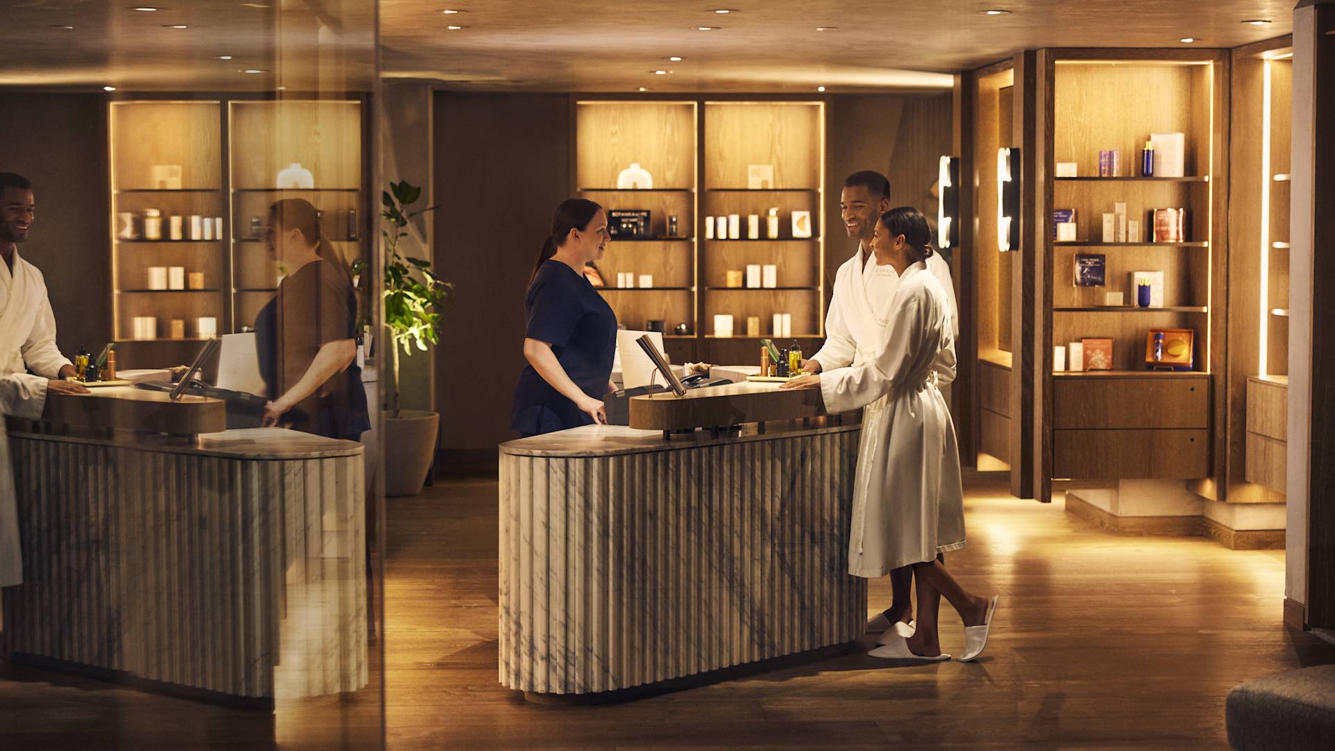 Man and woman in white robes arriving at spa reception area