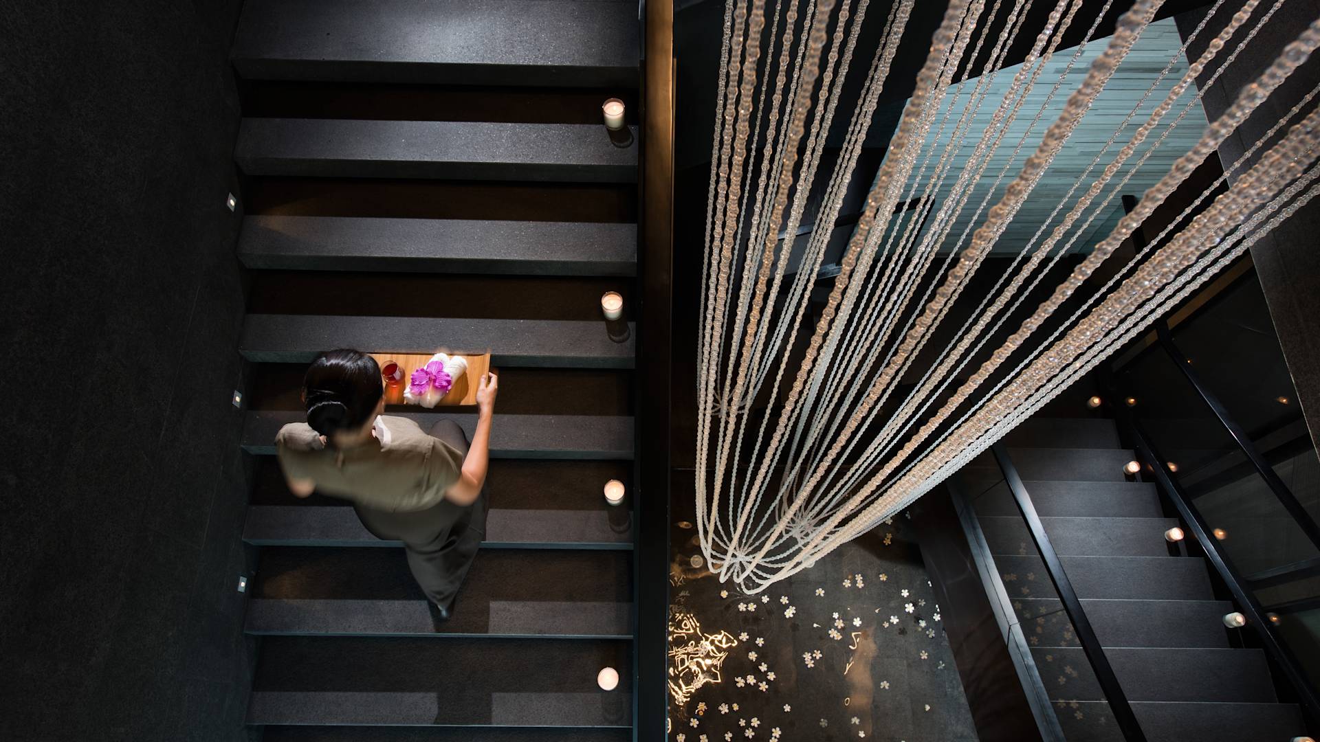 Femme portant des produits de spa dans un escalier