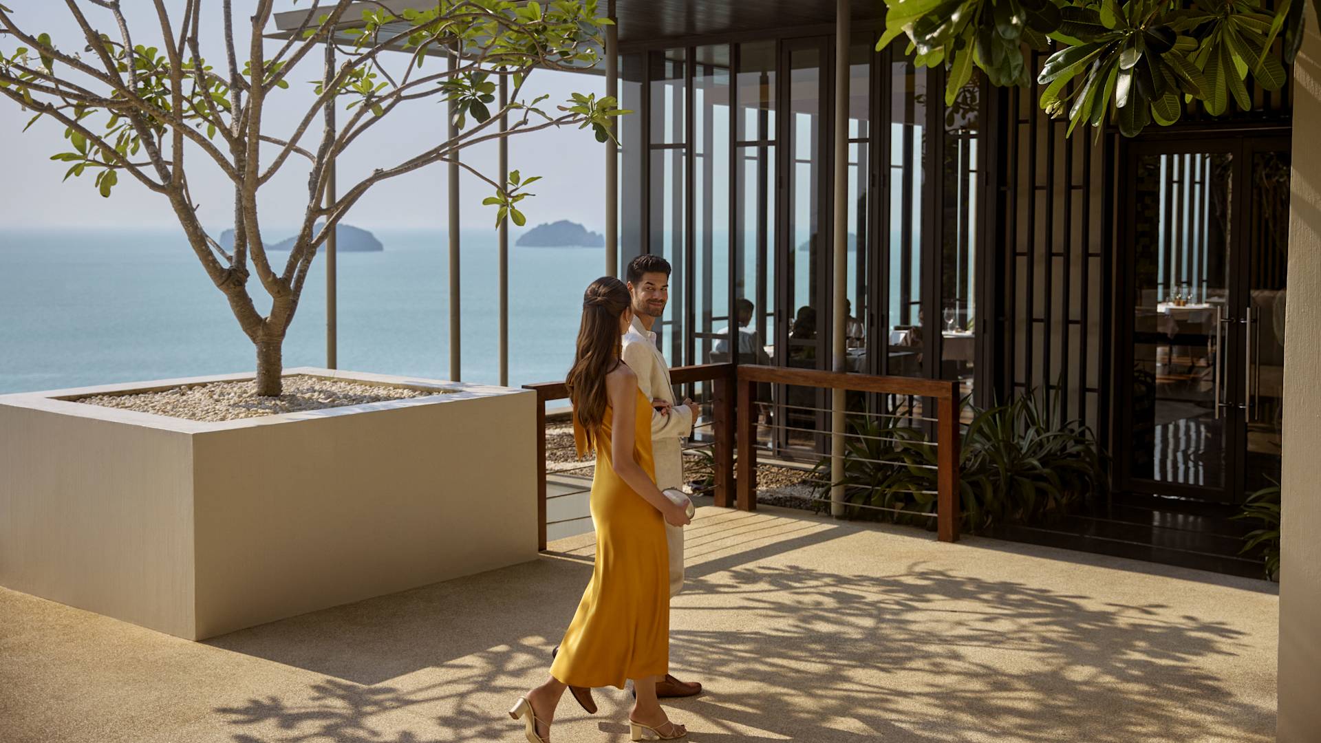 Un homme et une femme marchant devant l'arbre en direction de l'entrée du restaurant