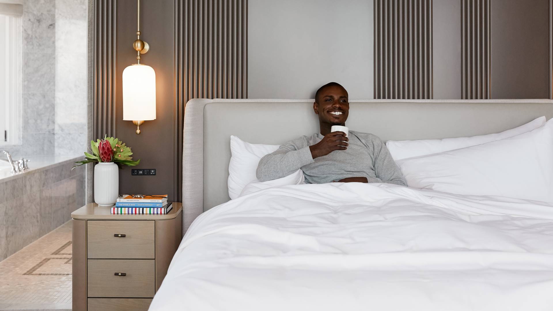 Man lying in bed drinking cup of coffee