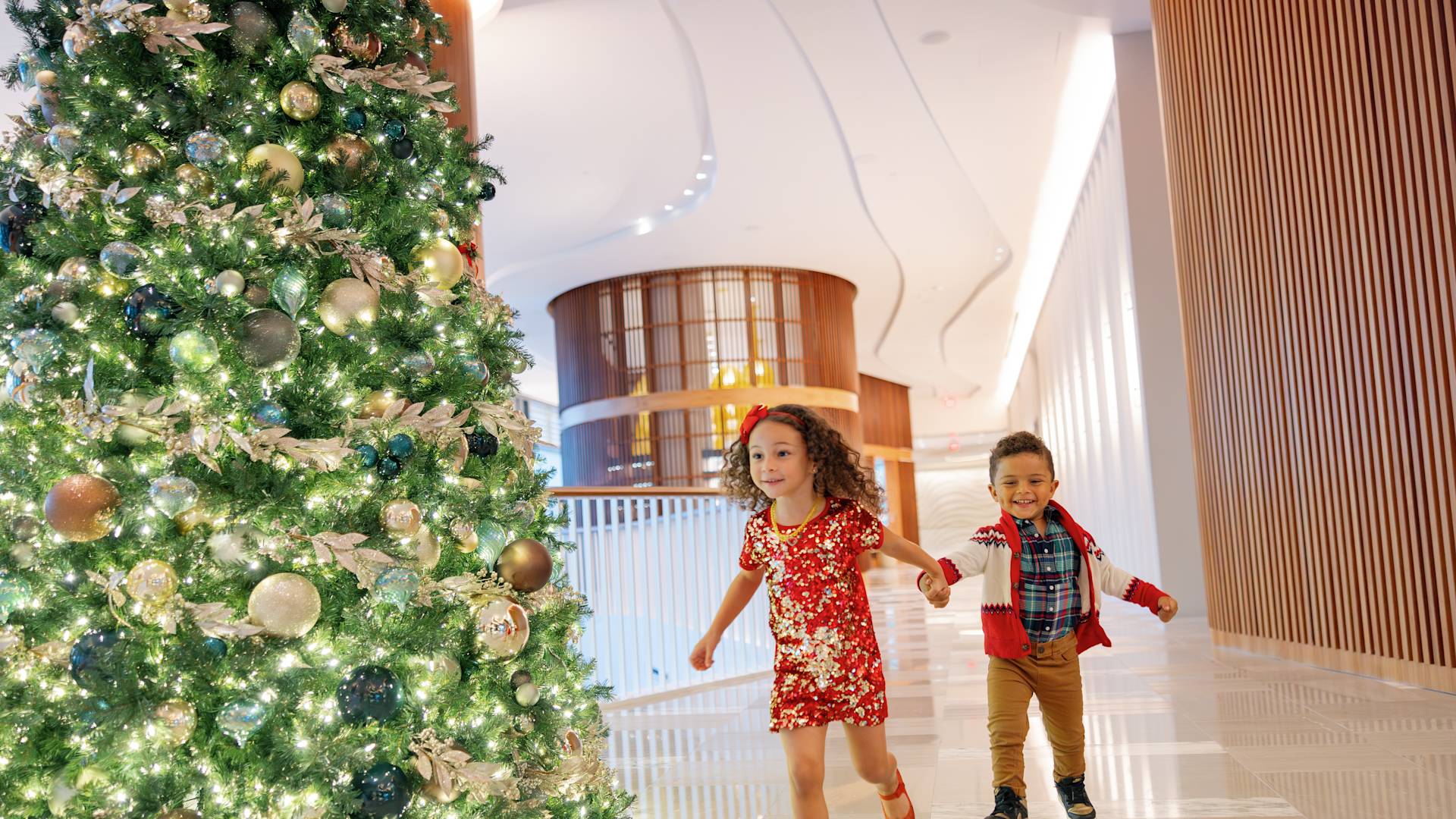 Kids Running in the Lobby Decorated with a Christmas Tree to Celebrate the Holidays