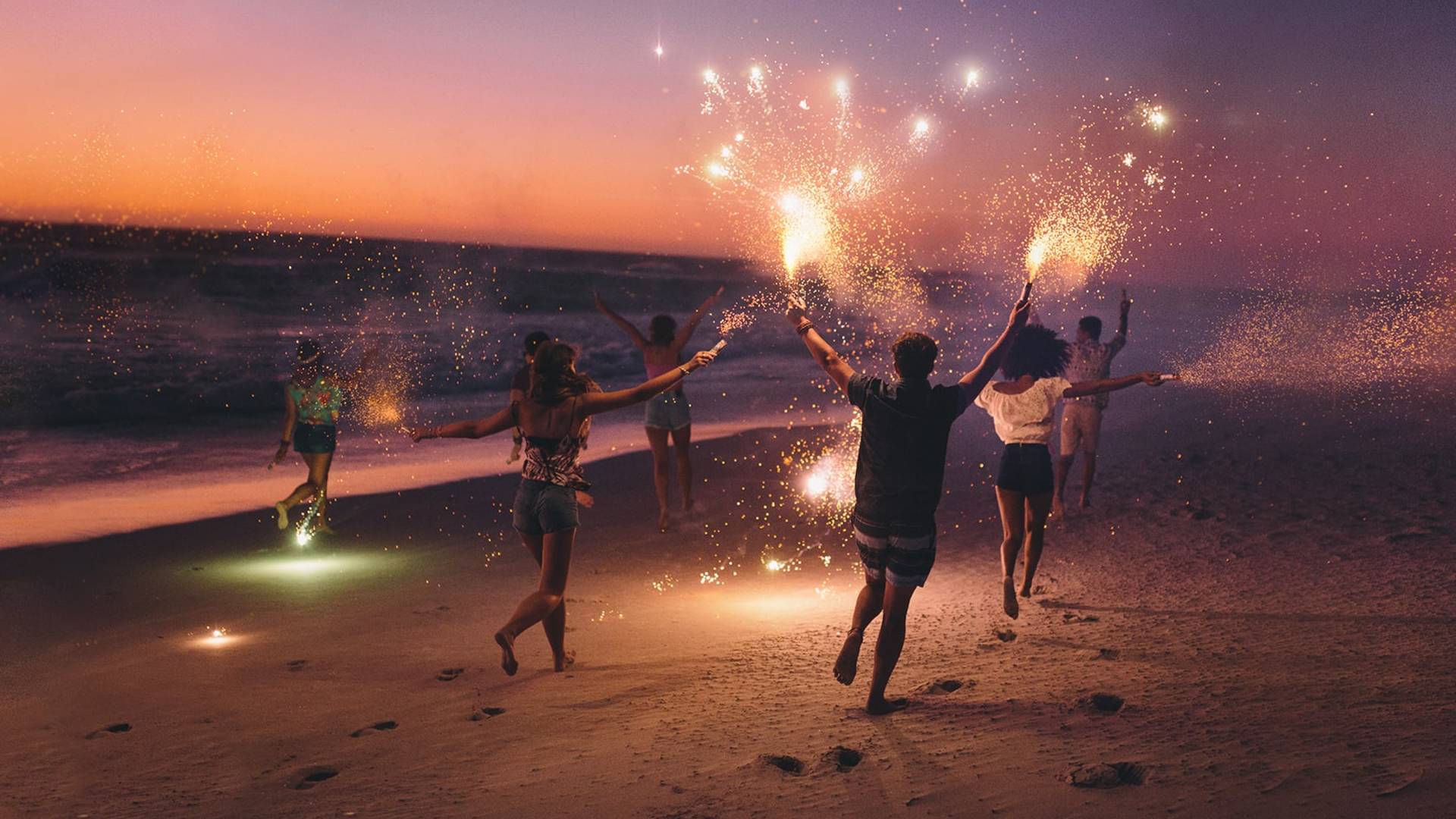 Des personnes sur la plage la nuit avec des scintilslements