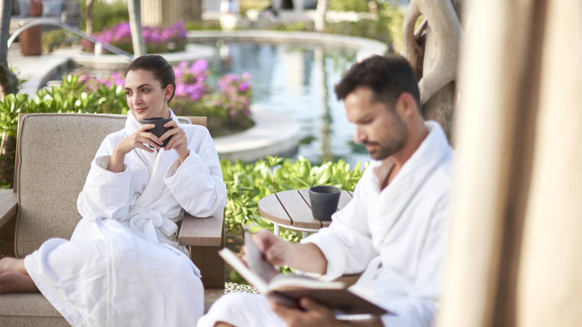 Couple sitting next to pool in Spa robes