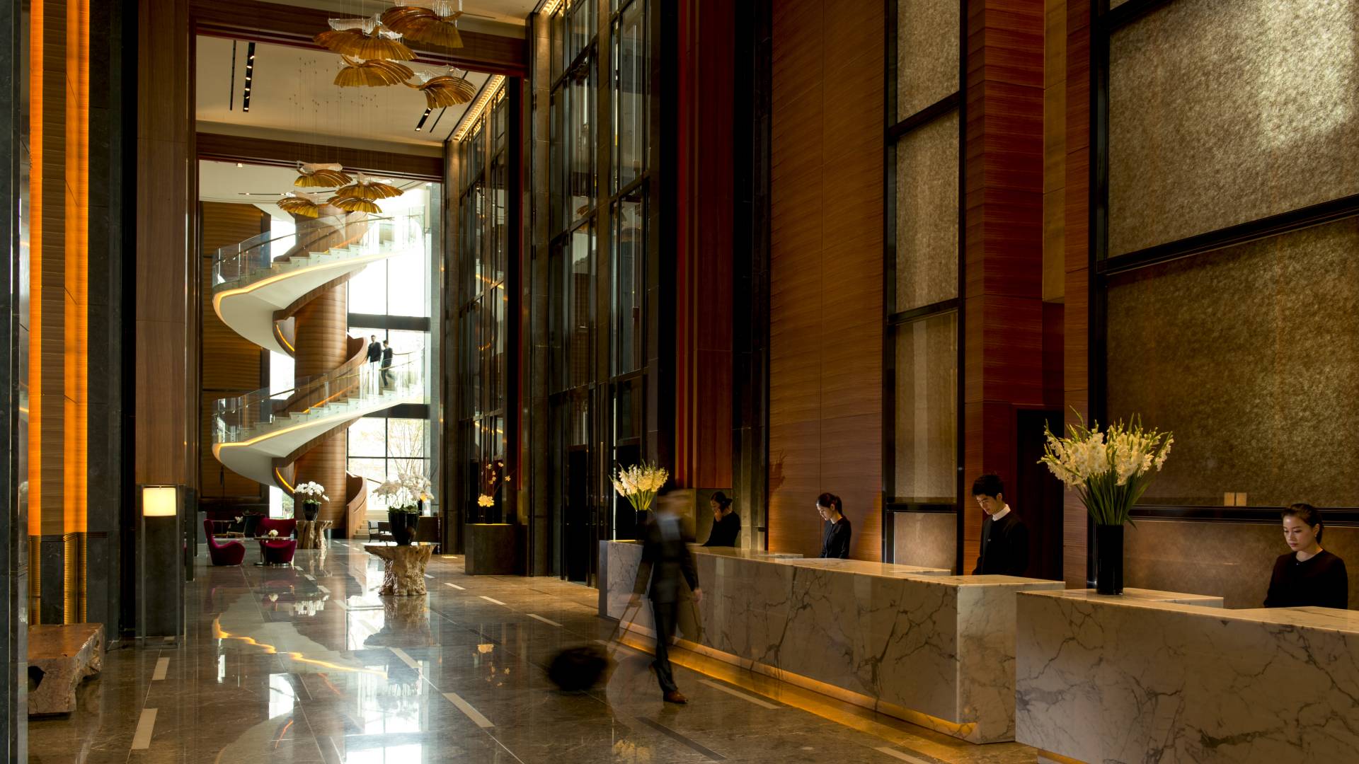 Geräumiger Lobbybereich im Conrad Seoul mit hohen Decken und Marmorböden. Im Hintergrund befindet sich eine Wendeltreppe.