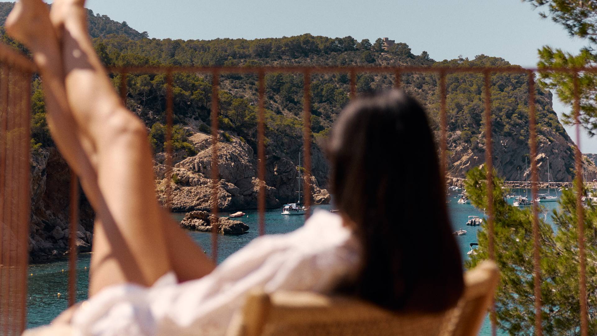 Frau, die sich auf dem Stuhl mit Booten mit Blick auf die Bucht entspannt