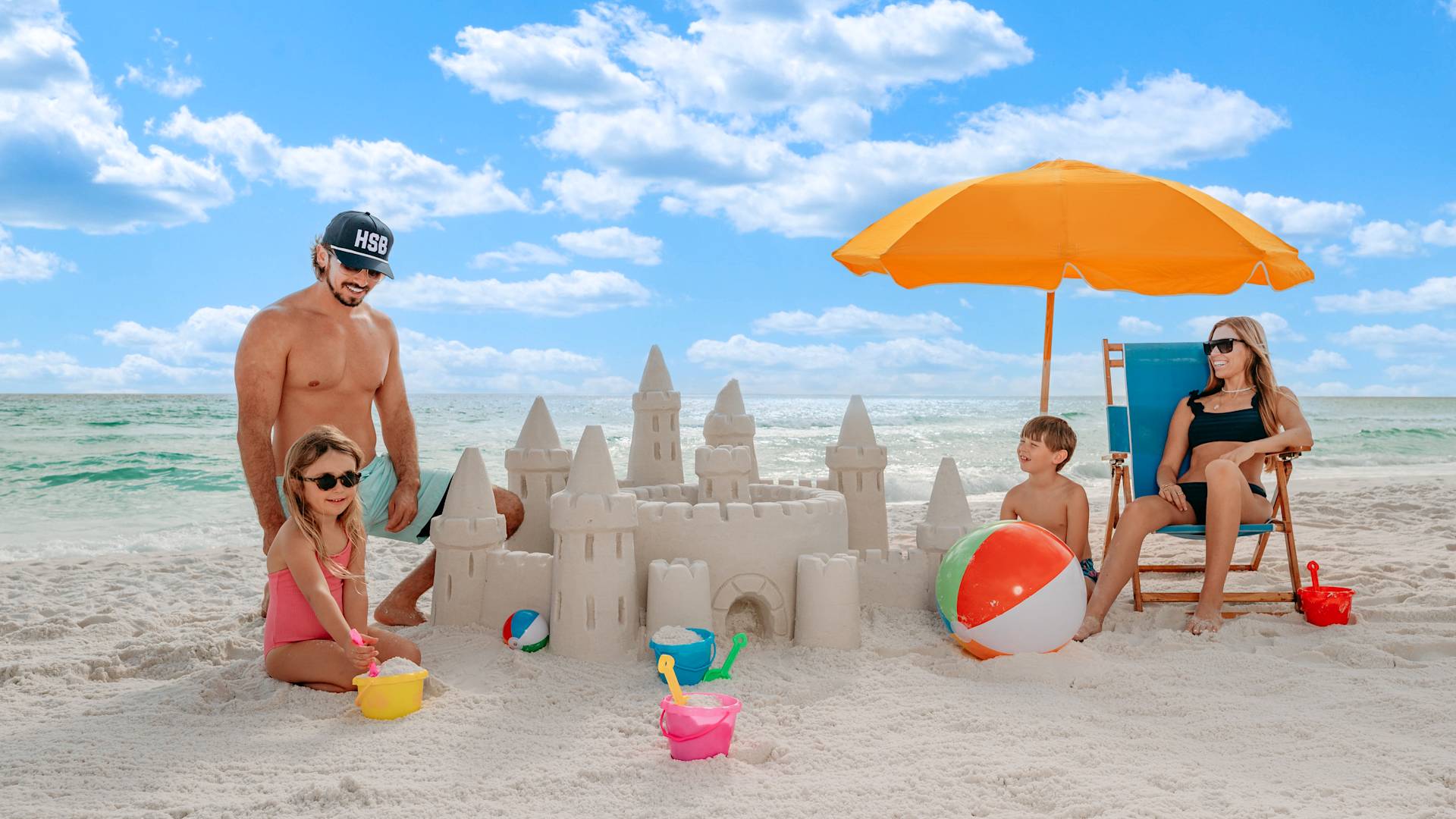 Familie jucându-se și făcând un castel de nisip pe plajă