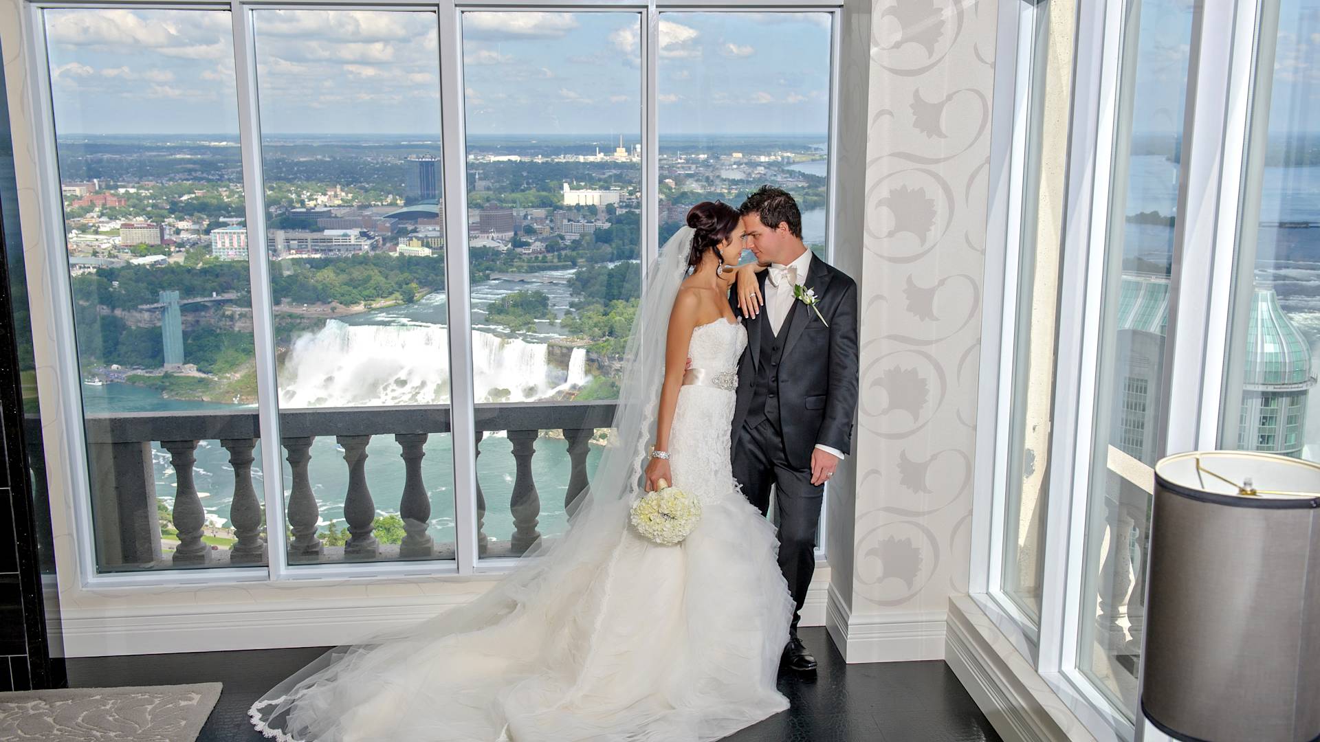 Newlyweds Holding in a Hotel Room with View of Niagara Falls