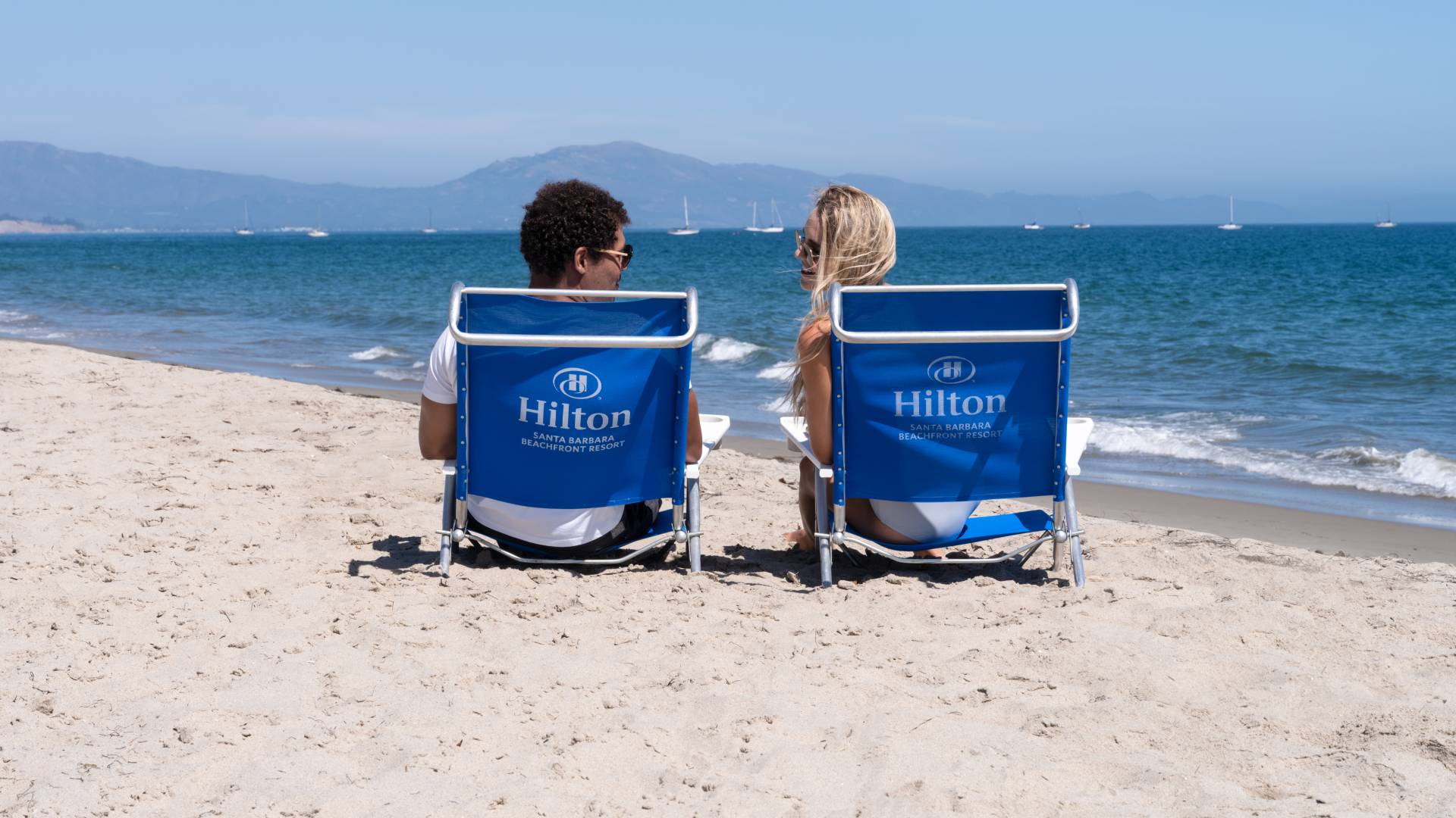 Couple Sitting on Lounge Chairs Talking at the Beach