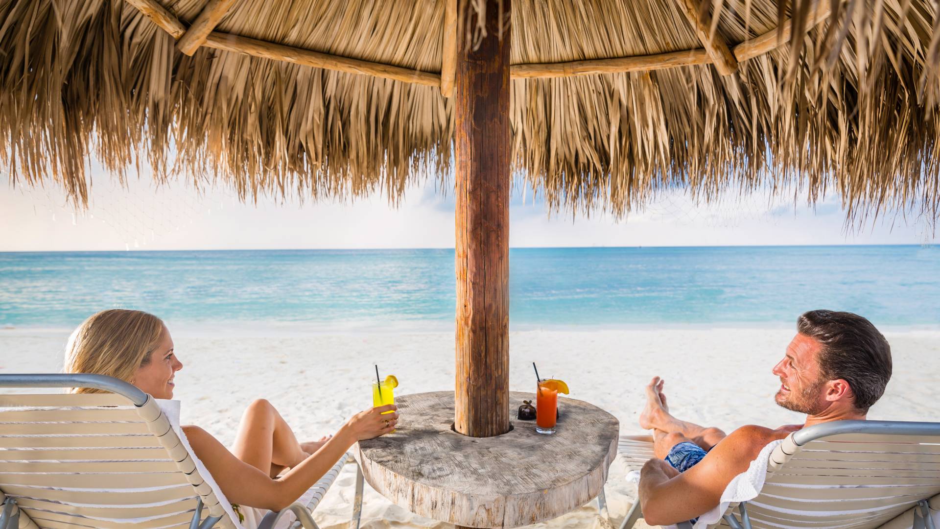 Couple Enjoying View and Cocktails Under Palapa at On-Site Beach