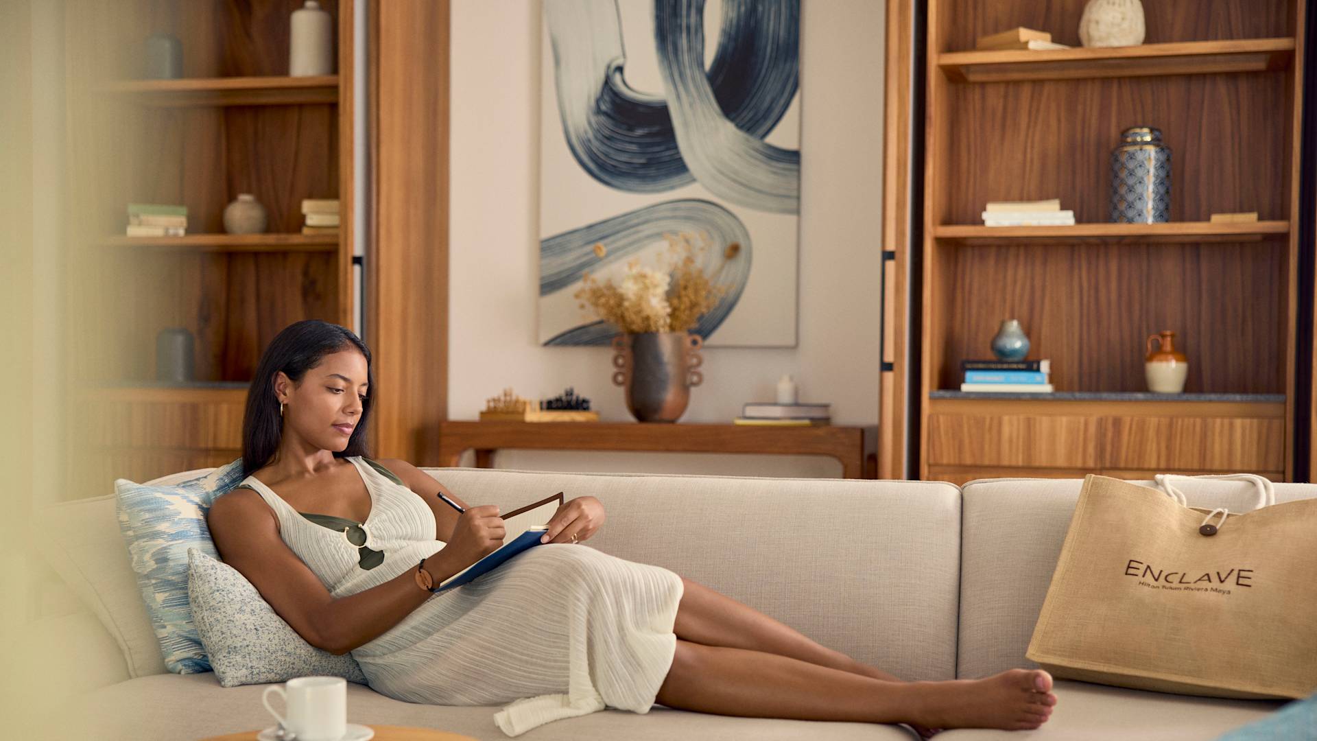 Femme se détendant sur le canapé d'une suite et écrivant dans un carnet de notes