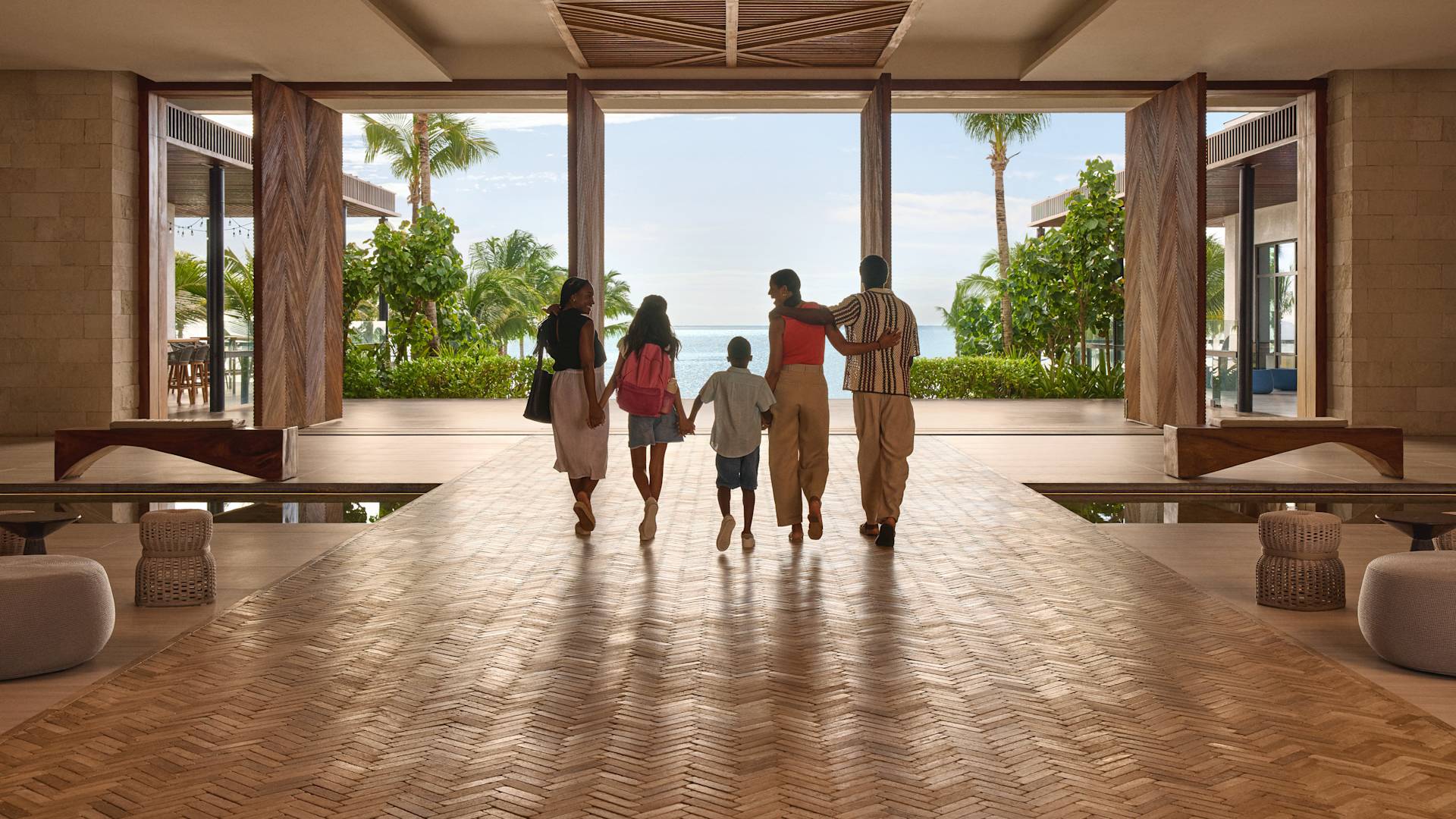 Two women, two children and one man walking through the hotel lobby holding hands