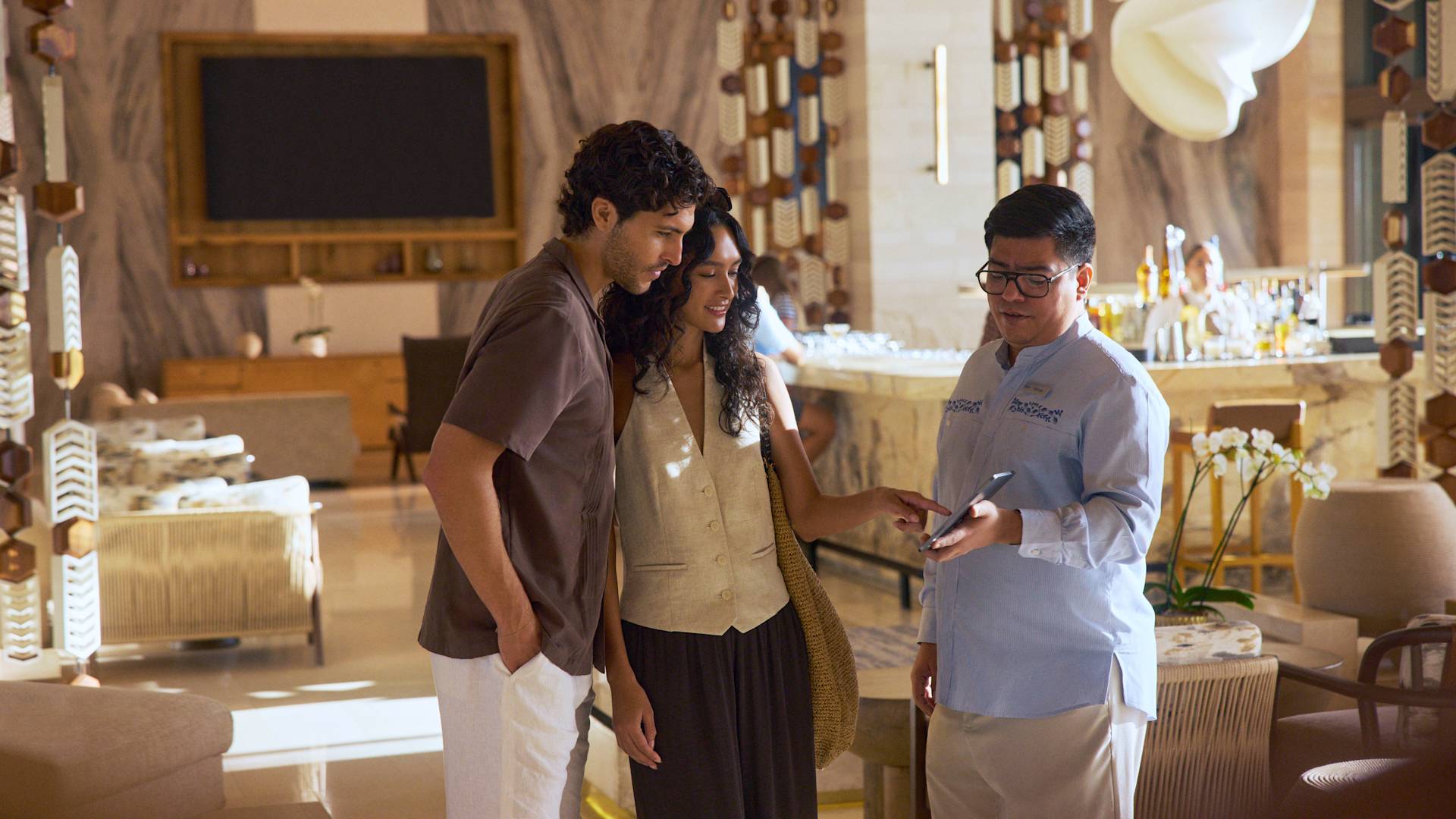 ผู้ชายและผู้หญิงกําลังคุยกับสมาชิกทีมงานที่แผนกต้อนรับ