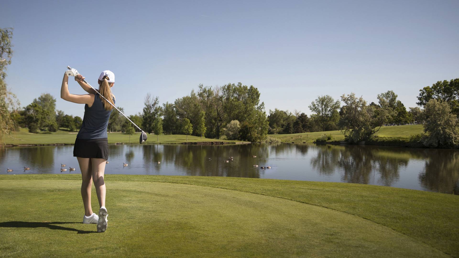 Golfer Hitting Ball over Pond