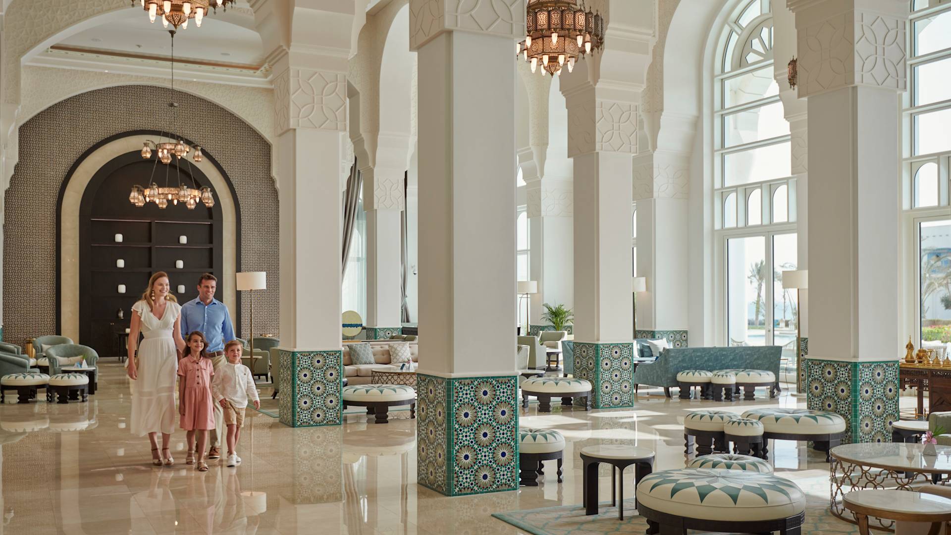 Familia caminando por el área del lobby con pilares y arcos.