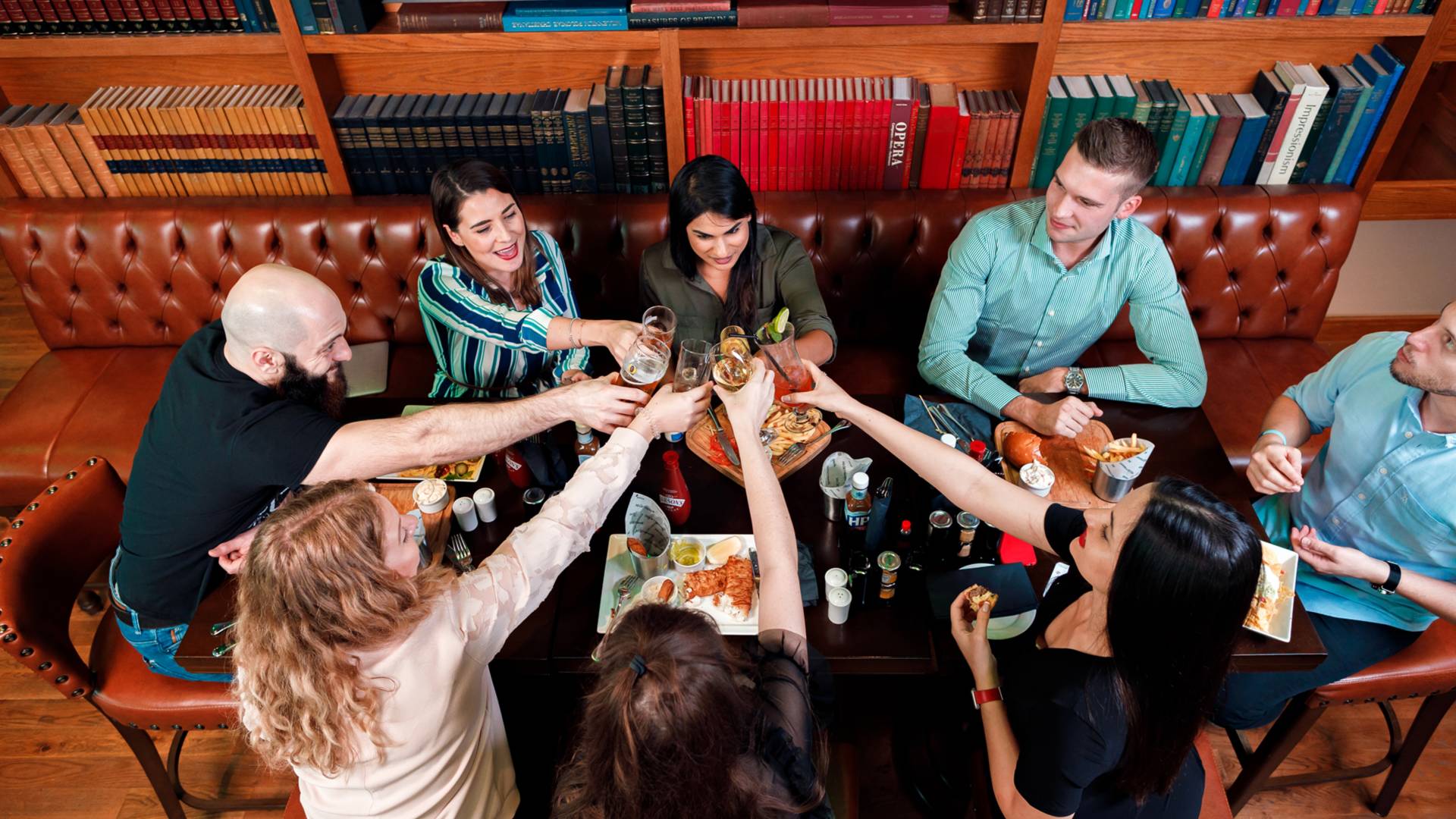 Group of friends sitting round table raising glasses