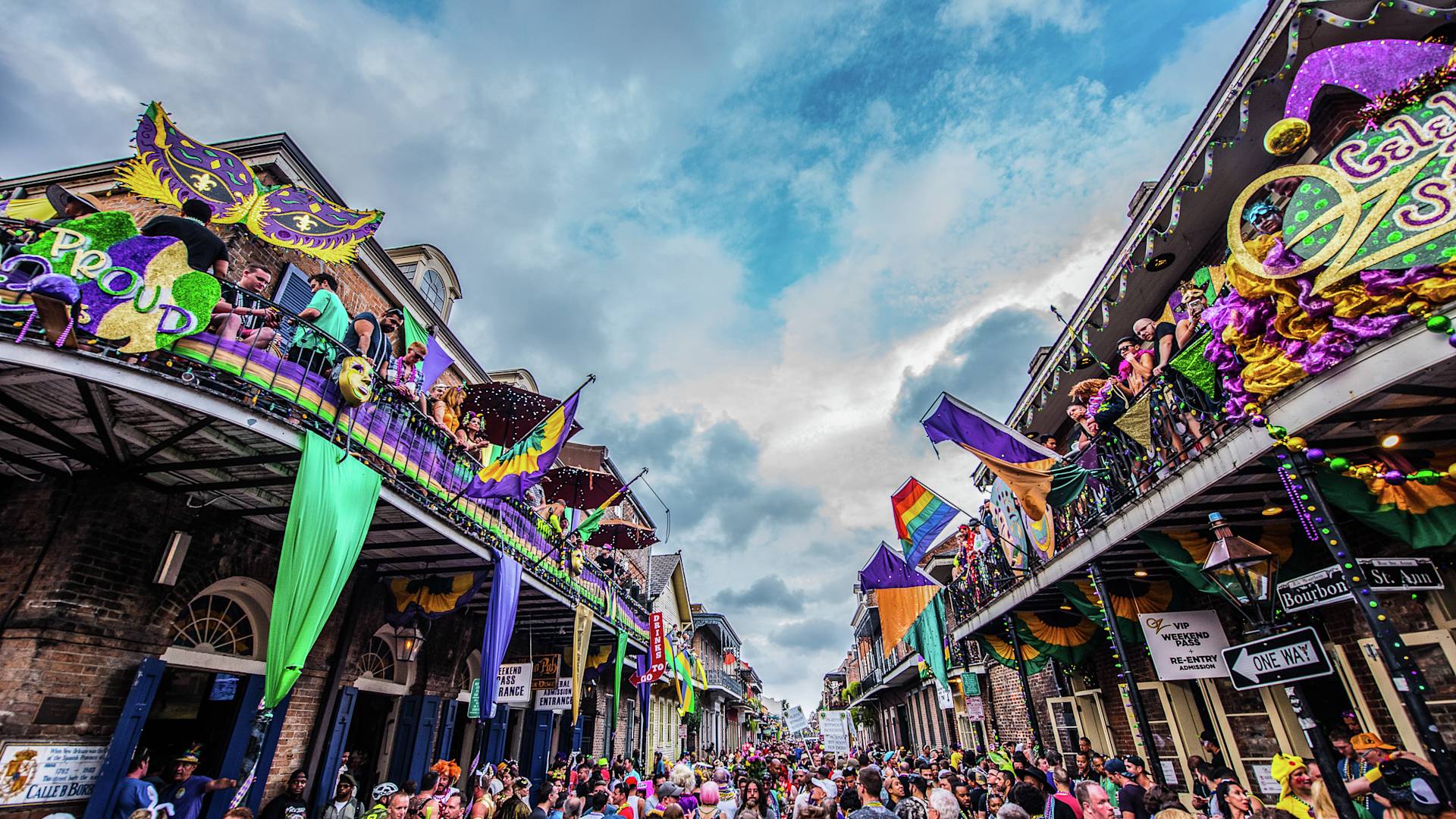 Stadtstraße in New Orleans mit Mardi Gras-Dekoration, Personen, die zu Fuß gehen und auf Balkonen stehen