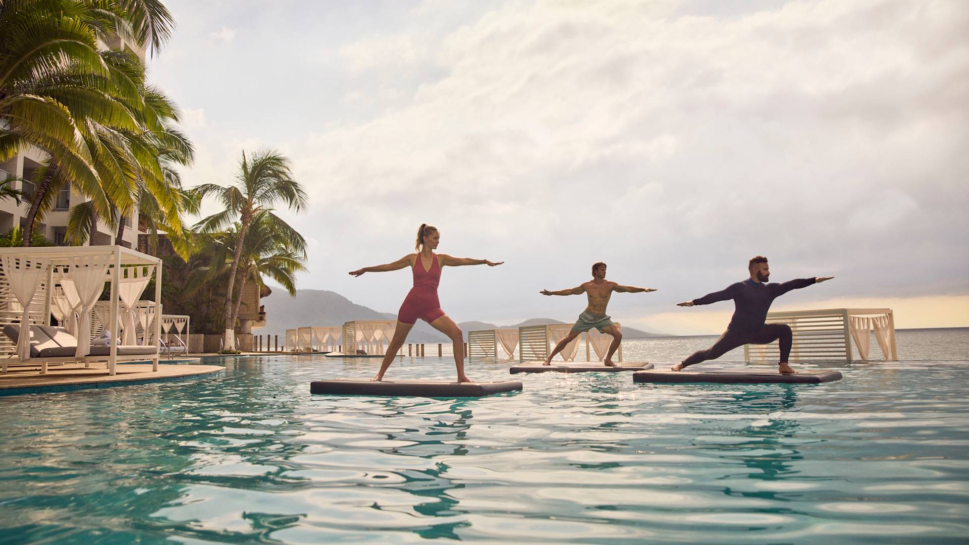 プールで水上ヨガを練習する女性と2人の男性