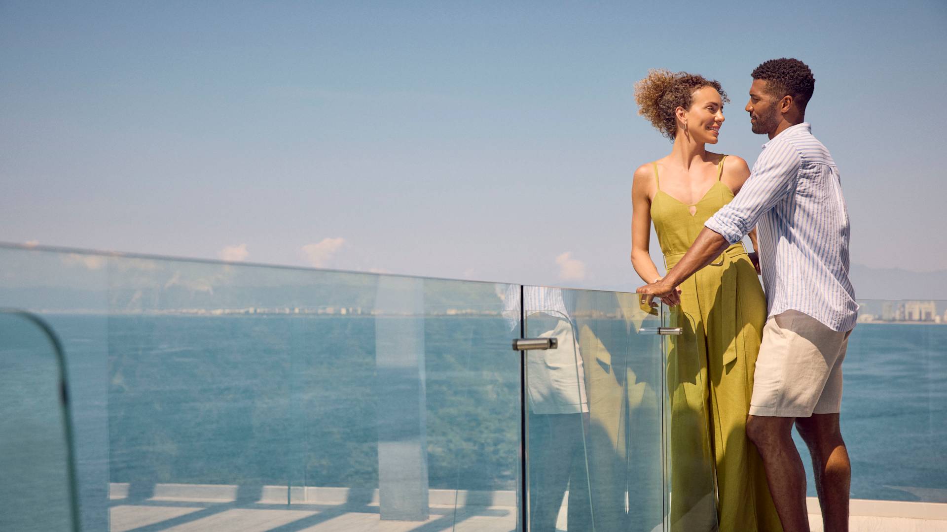 Woman and man looking at each other on the balcony of their sea view suite