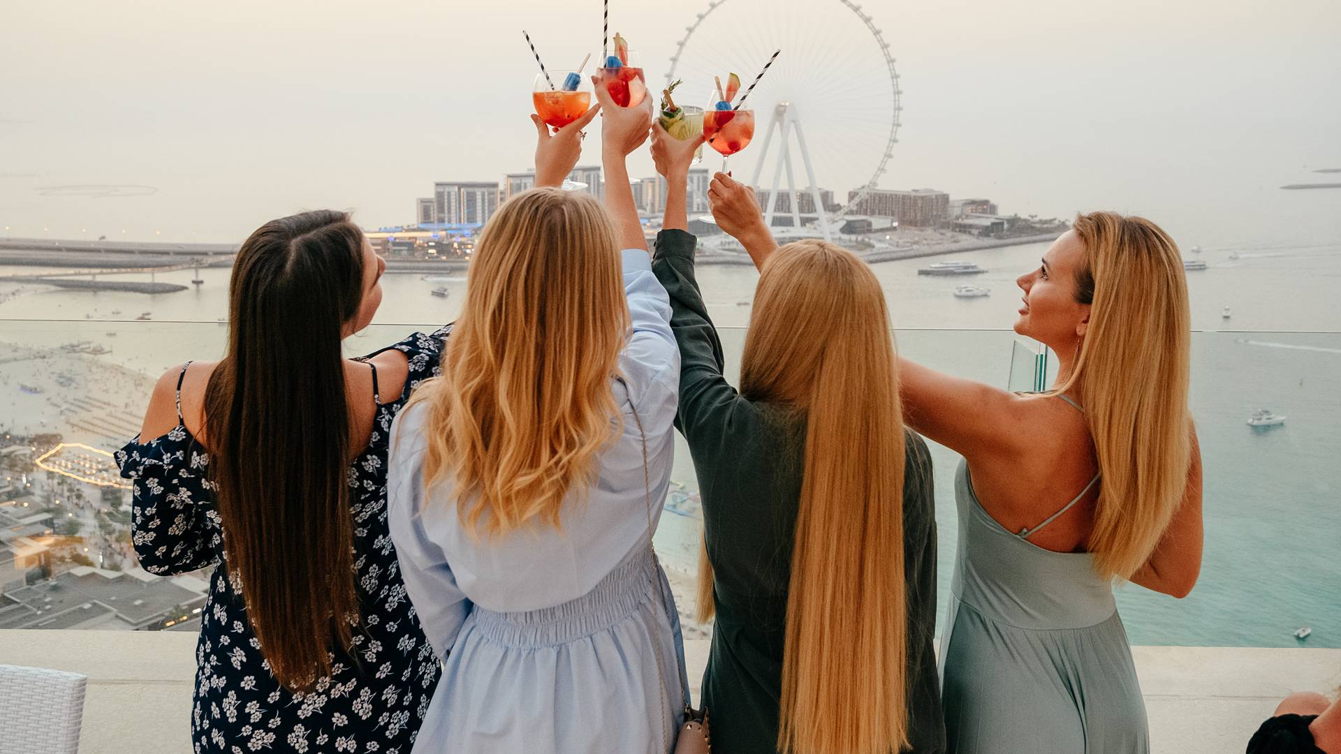 Group of women toasting their drinks with the Dubai Eye in the background