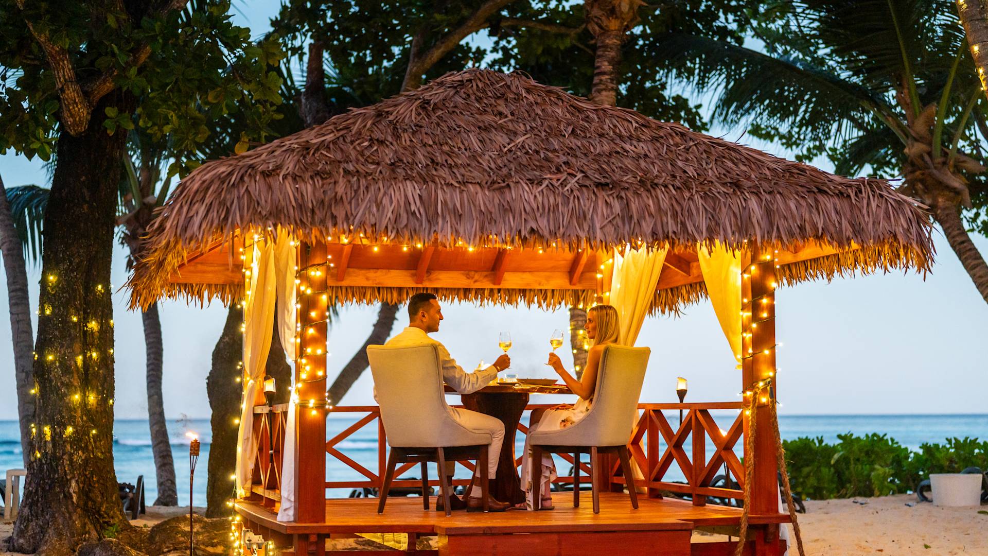 Couple Enjoying a Candlelight Dinner on a Covered Area Outdoors with Views of the Water