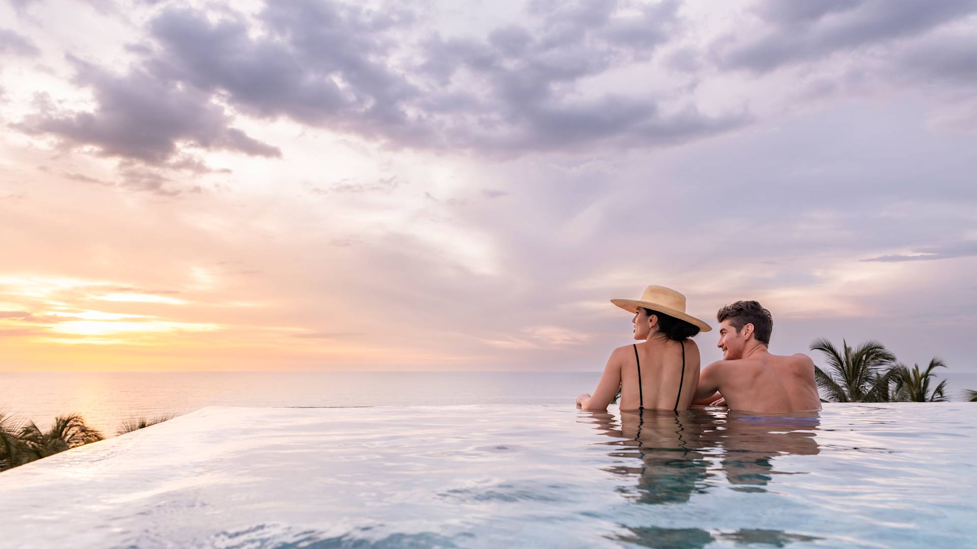 プールで海を眺めながらリラックスする男女