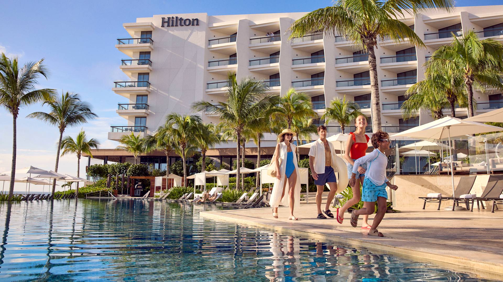 Mother and father walking with their son and daughter past the hotel pool