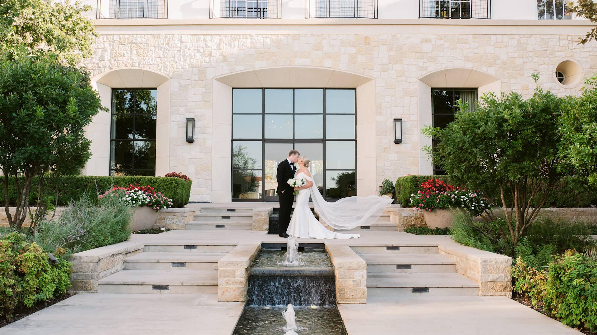 Bride and Groom  Kissing on Hotel Exterior Entrance with  Decorative Fountains