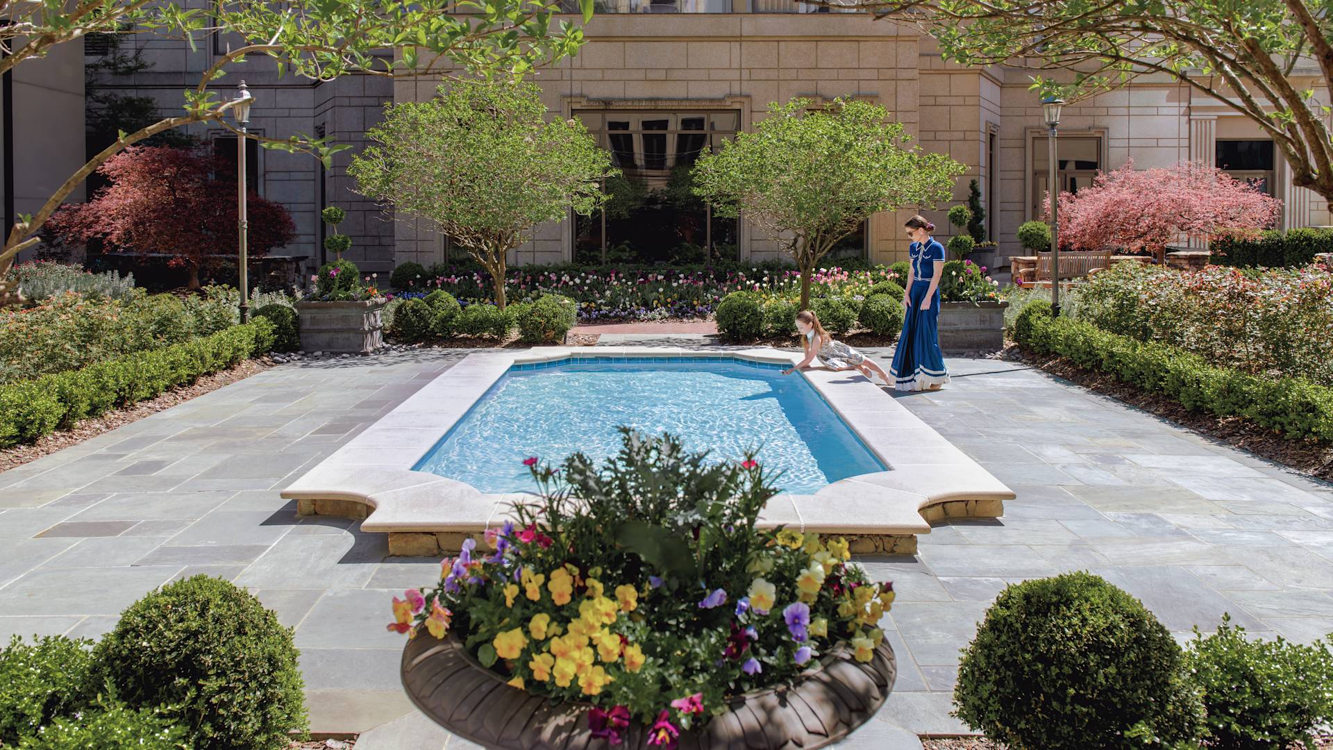 Outdoor pool area with trees and flowers