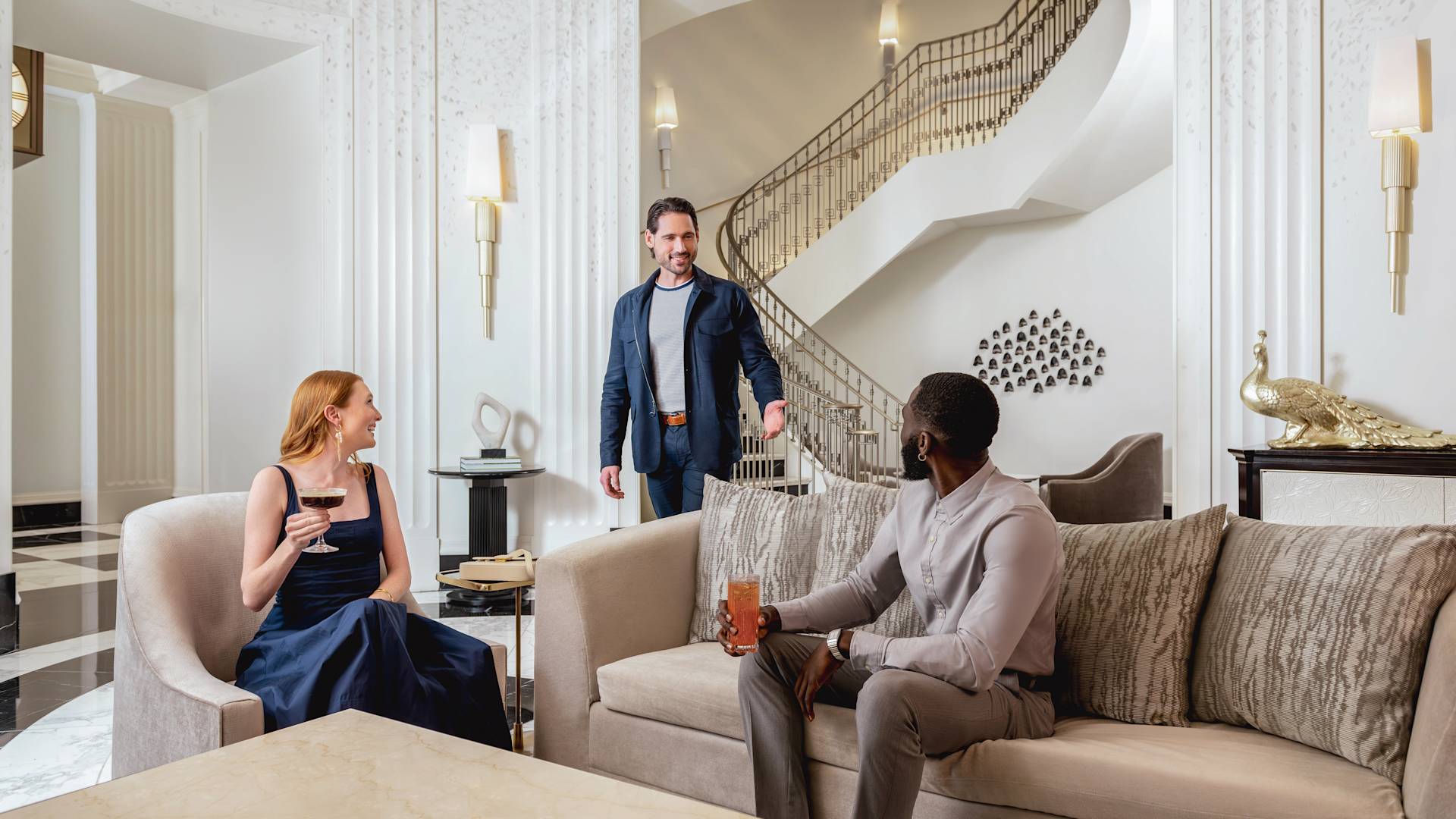 Man and woman sitting in comfortable lobby as another man approaches