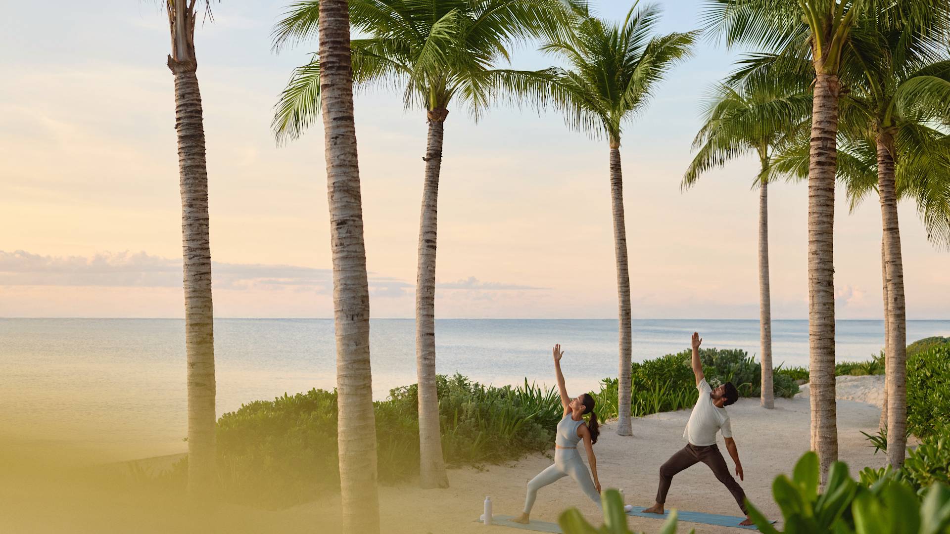 Мужчина и женщина занимаются йогой на пляже