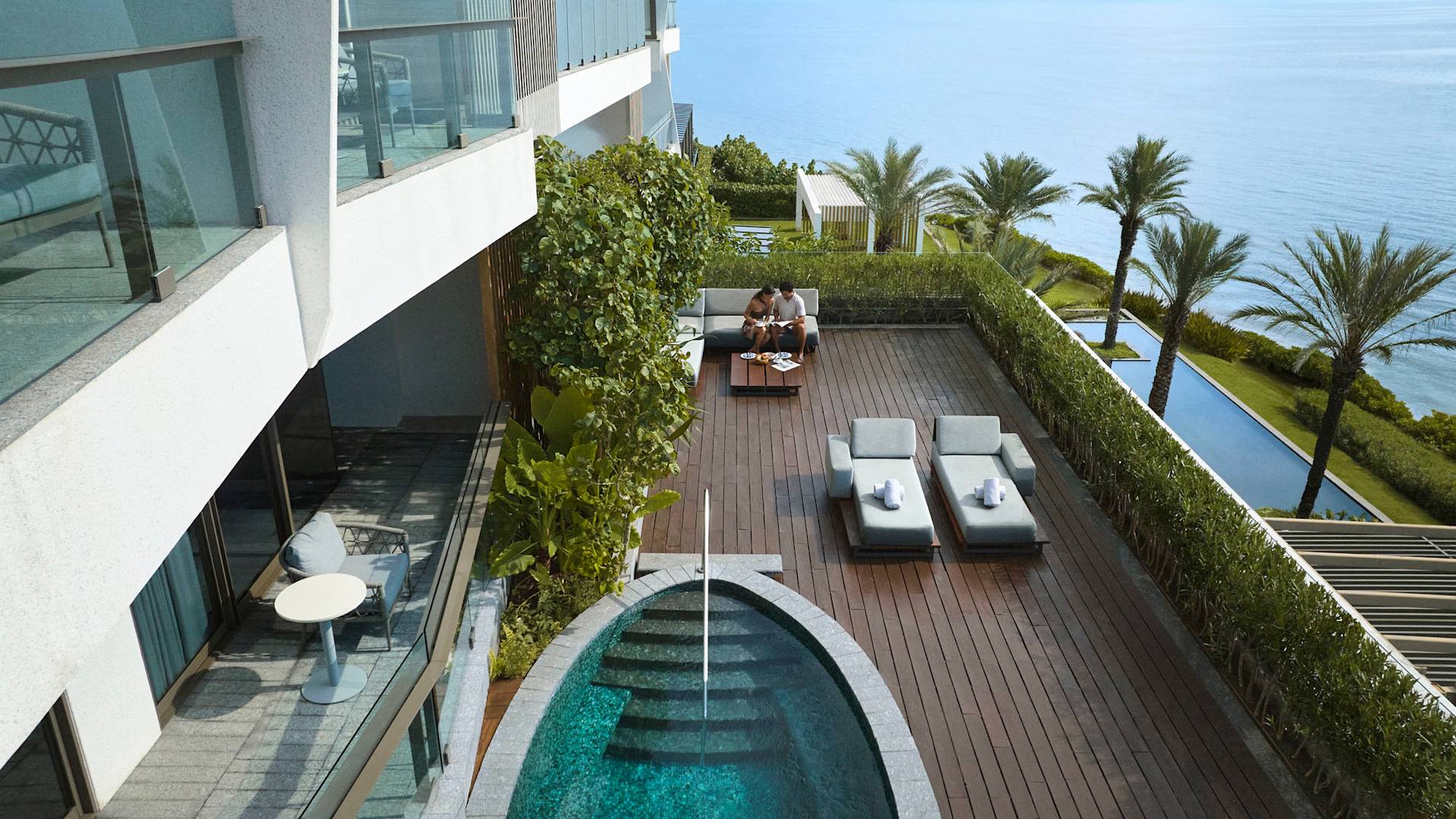 Man and woman relaxing on the patio of their suite with private pool