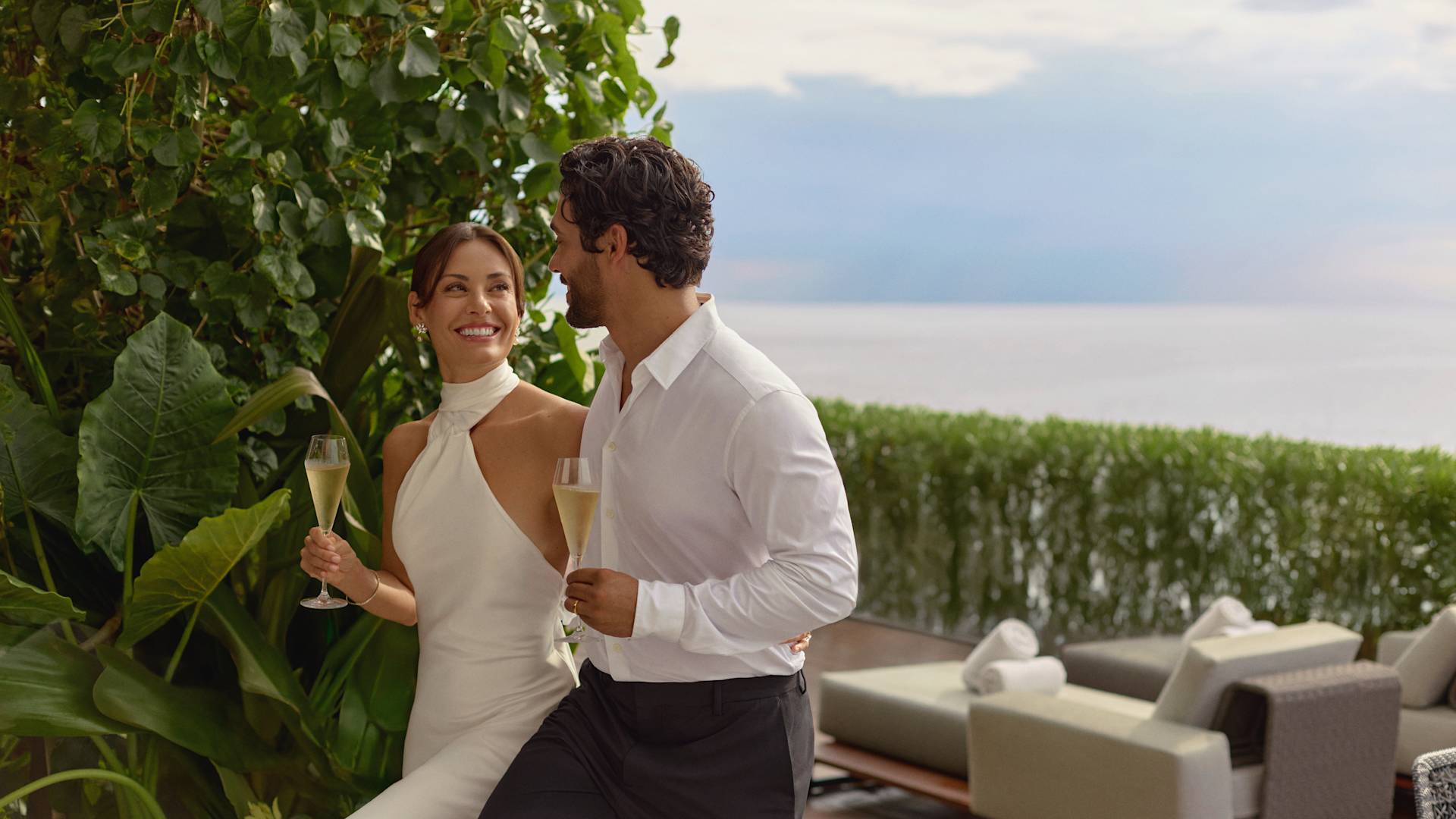 Mujer y hombre disfrutando de champán en la terraza de su suite