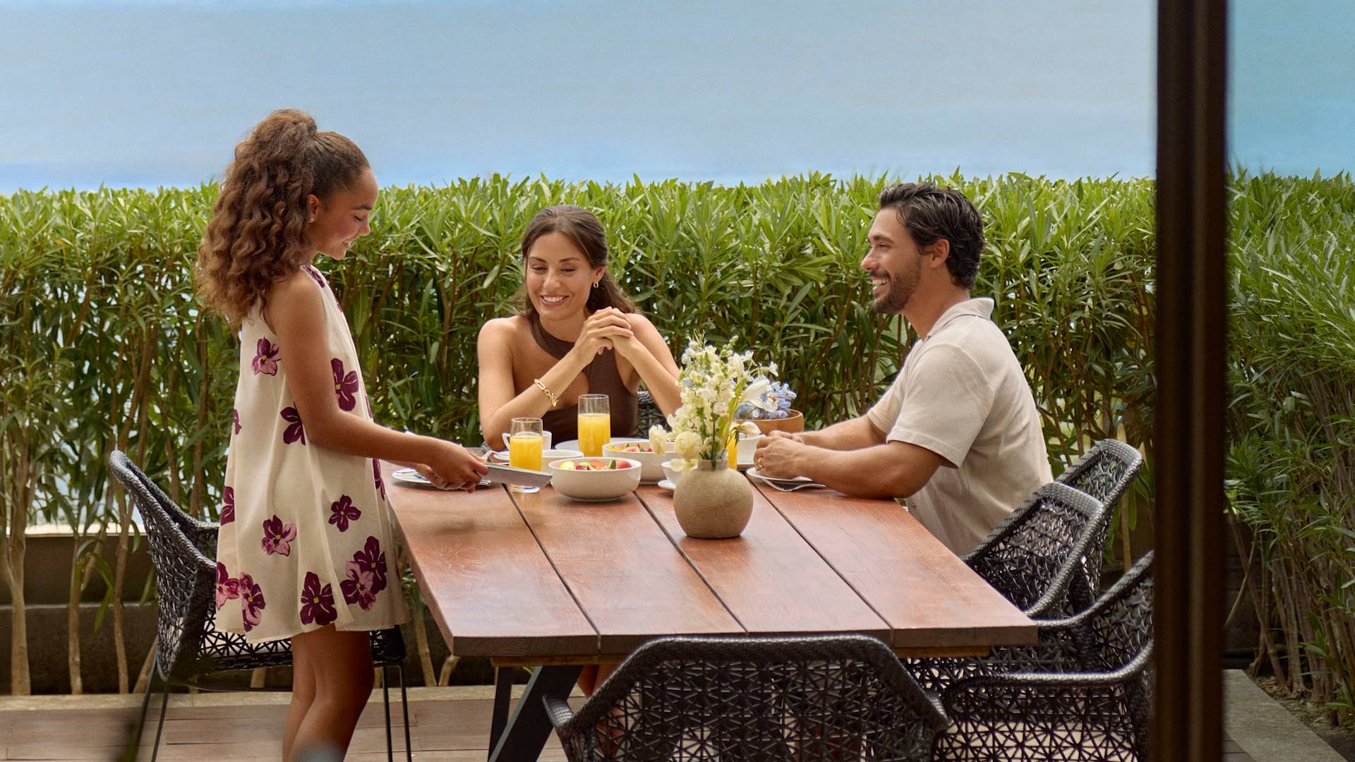 Mutter, Vater und Tochter genießen Frühstück auf der Terrasse ihrer Suite