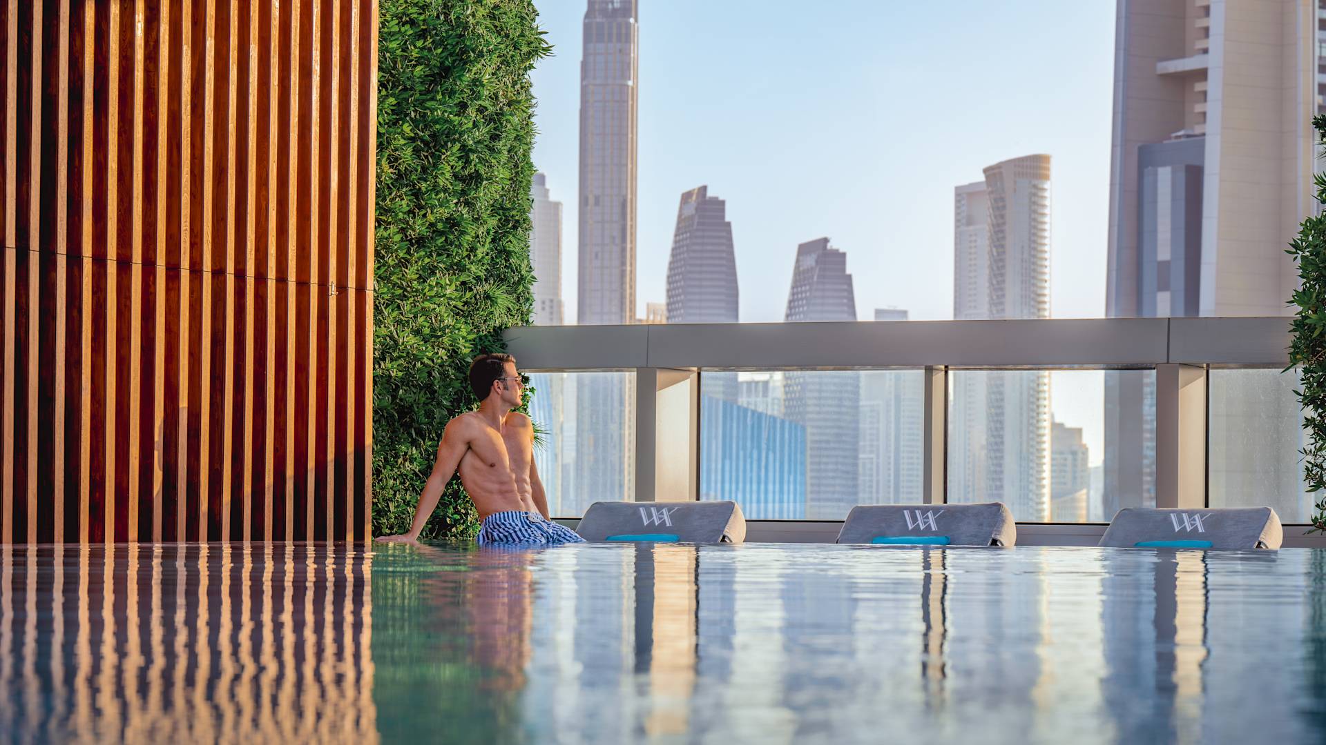 Man relaxing at edge of pool with city view