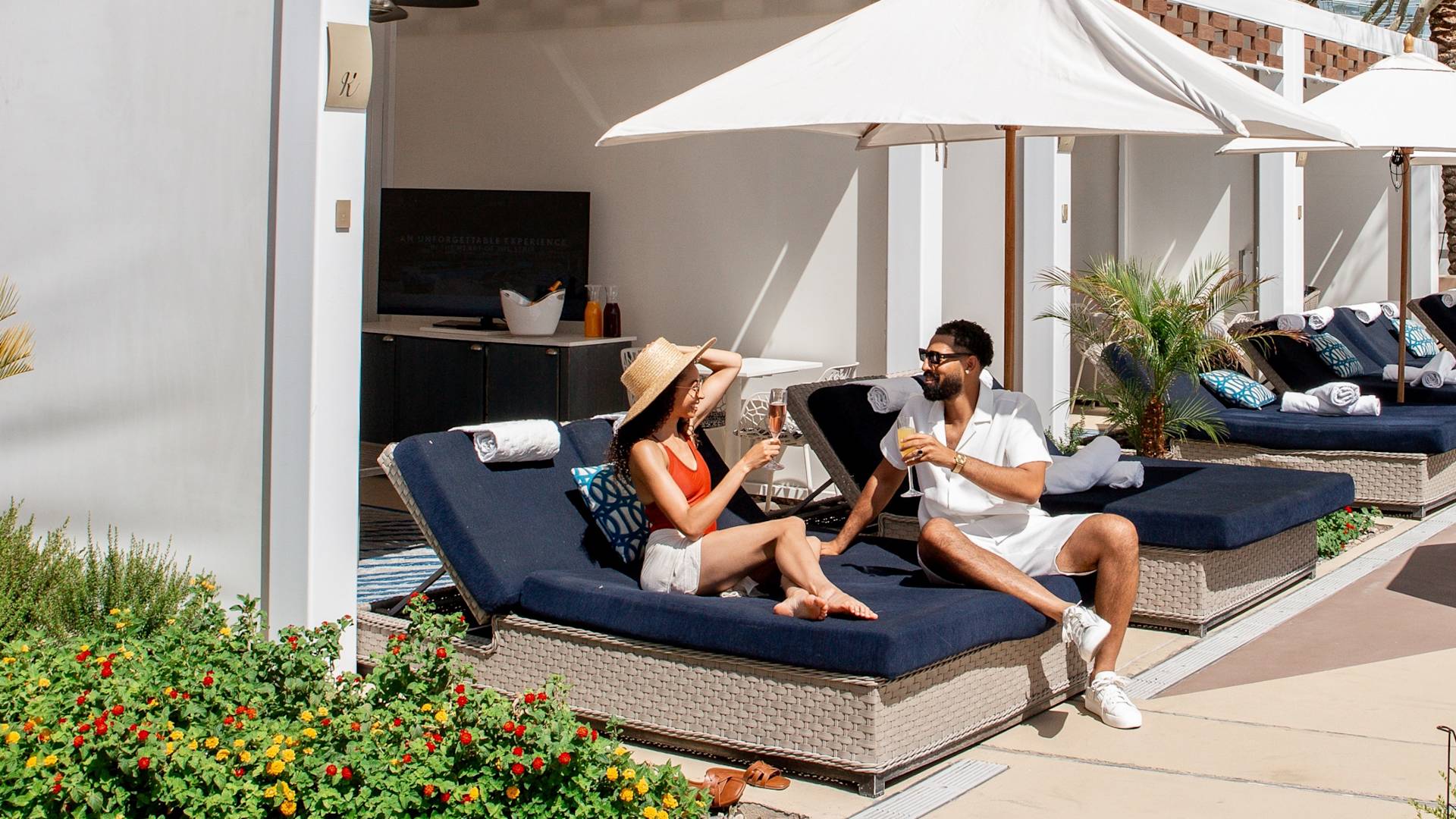 guests in a pool cabana having a cocktail, umbrellas, palm trees