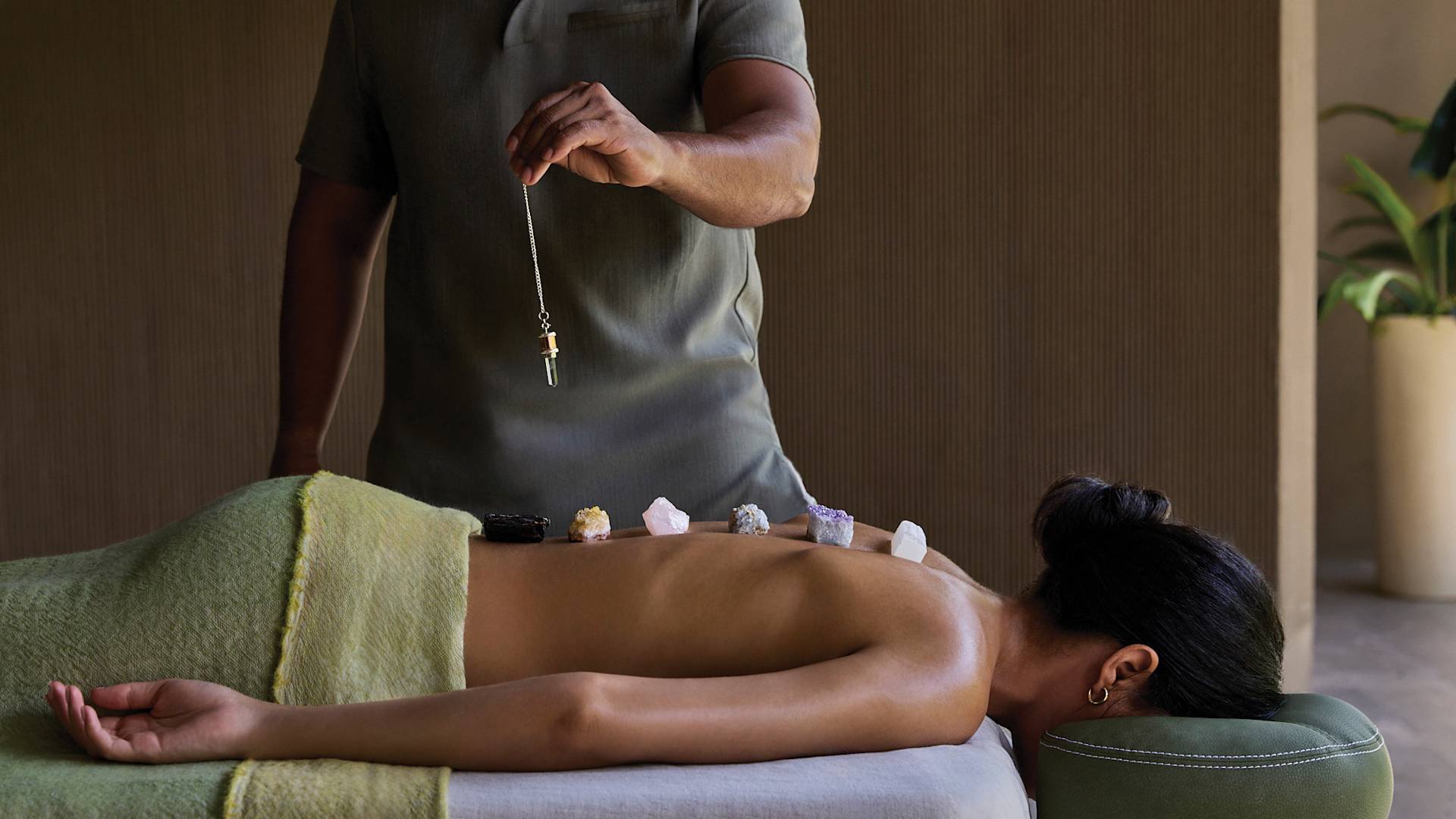 Femme sur une table de massage avec masseuse appliquant des pierres