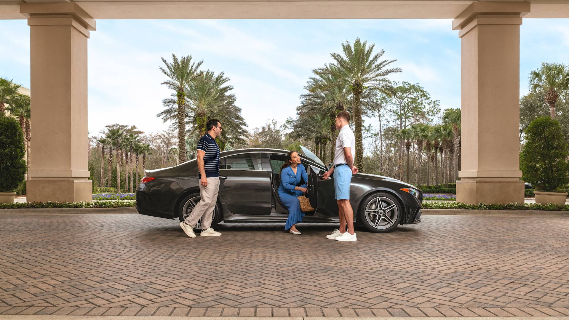 Femme sortant de la voiture dans l'allée. Un membre du personnel tient la porte du véhicule