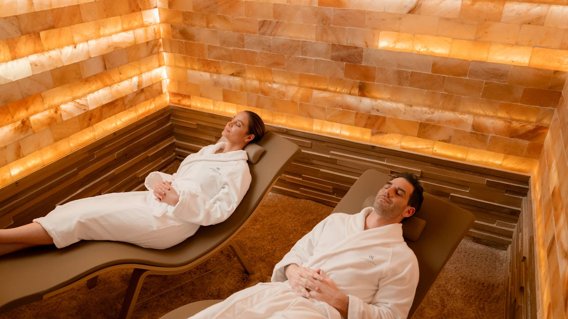 Man and woman relaxing on lounger in robes