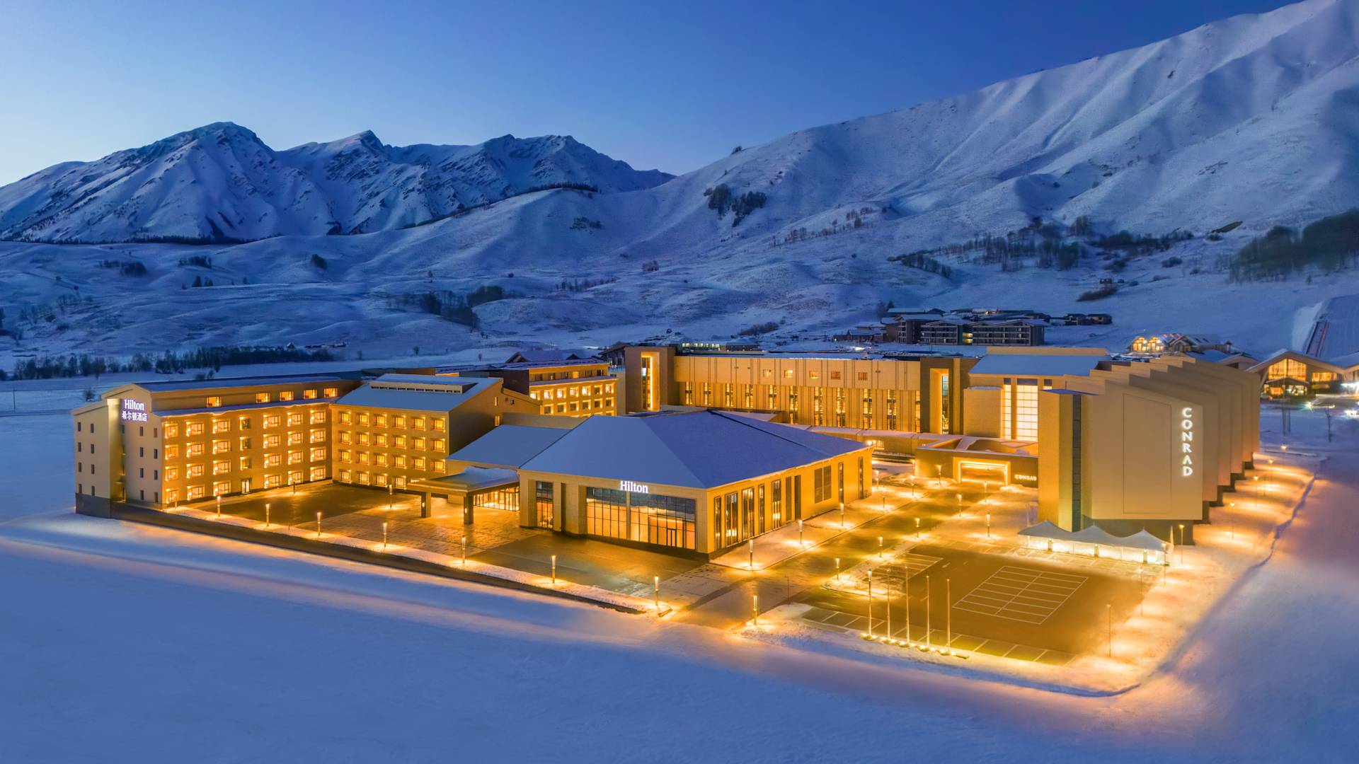 Osvětlený exteriér hotelu s okolními zasněženými horami