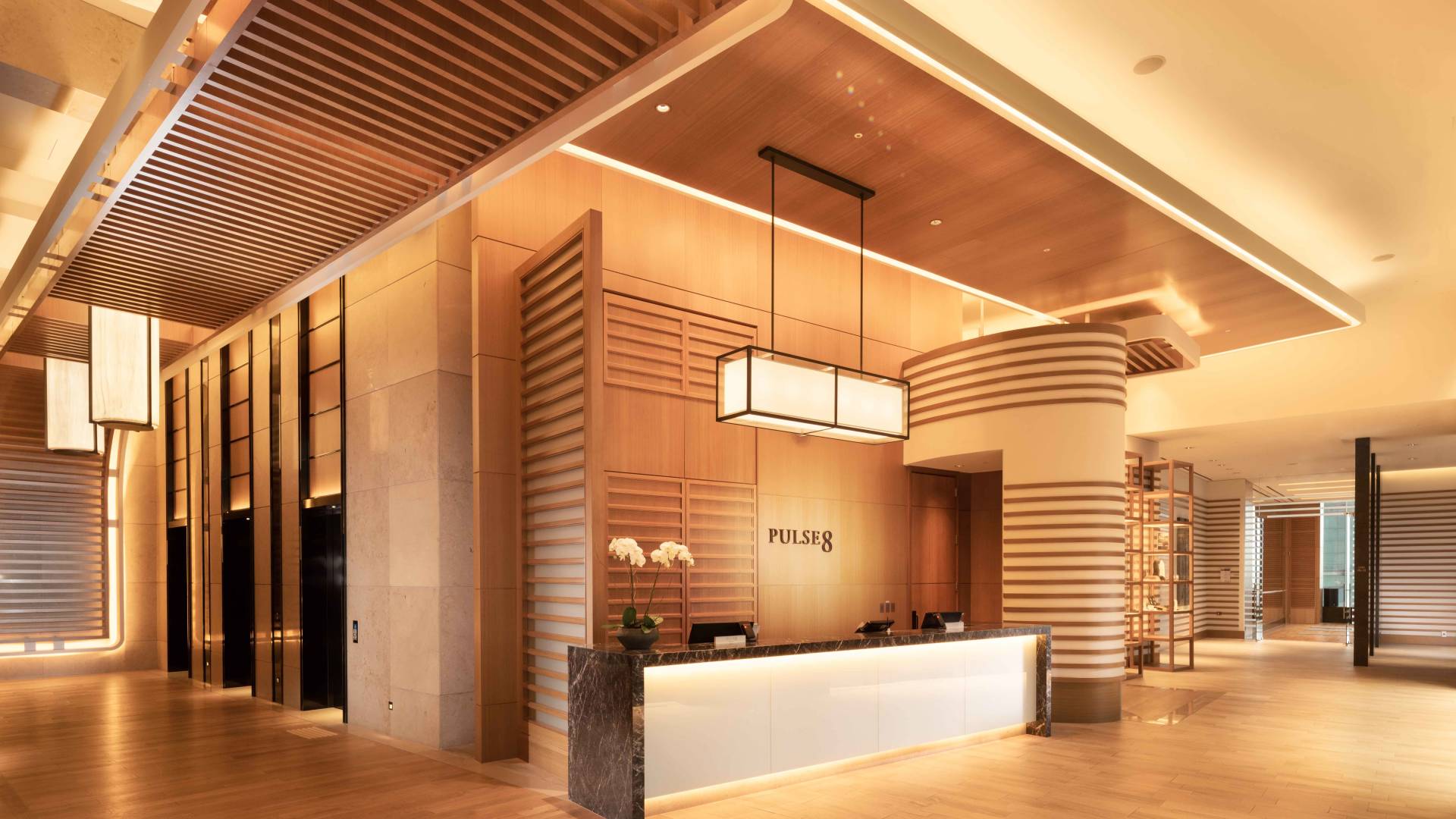 Pulse8 Reception desk. Decorative wood paneling and warm, modern lighting complete the space.