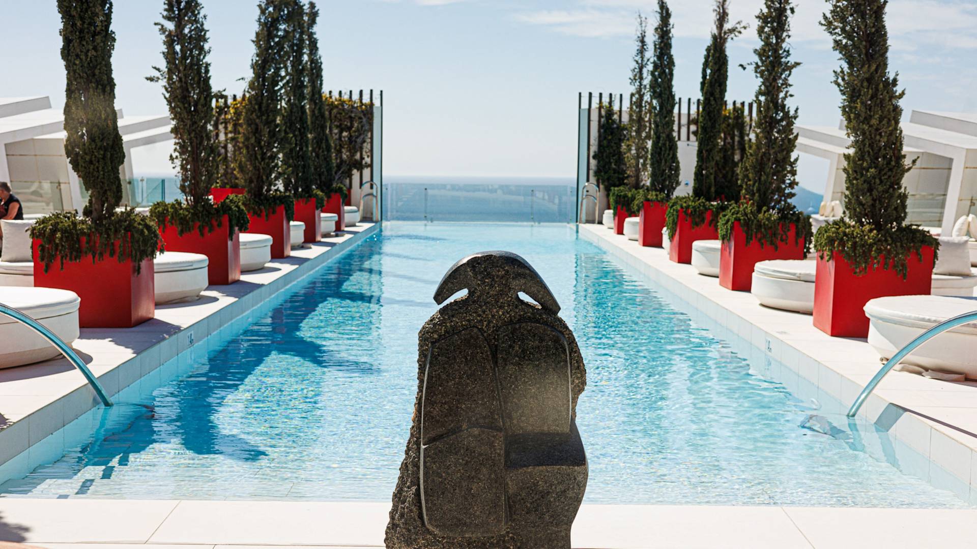 outdoor pool lined with trees, stone statue