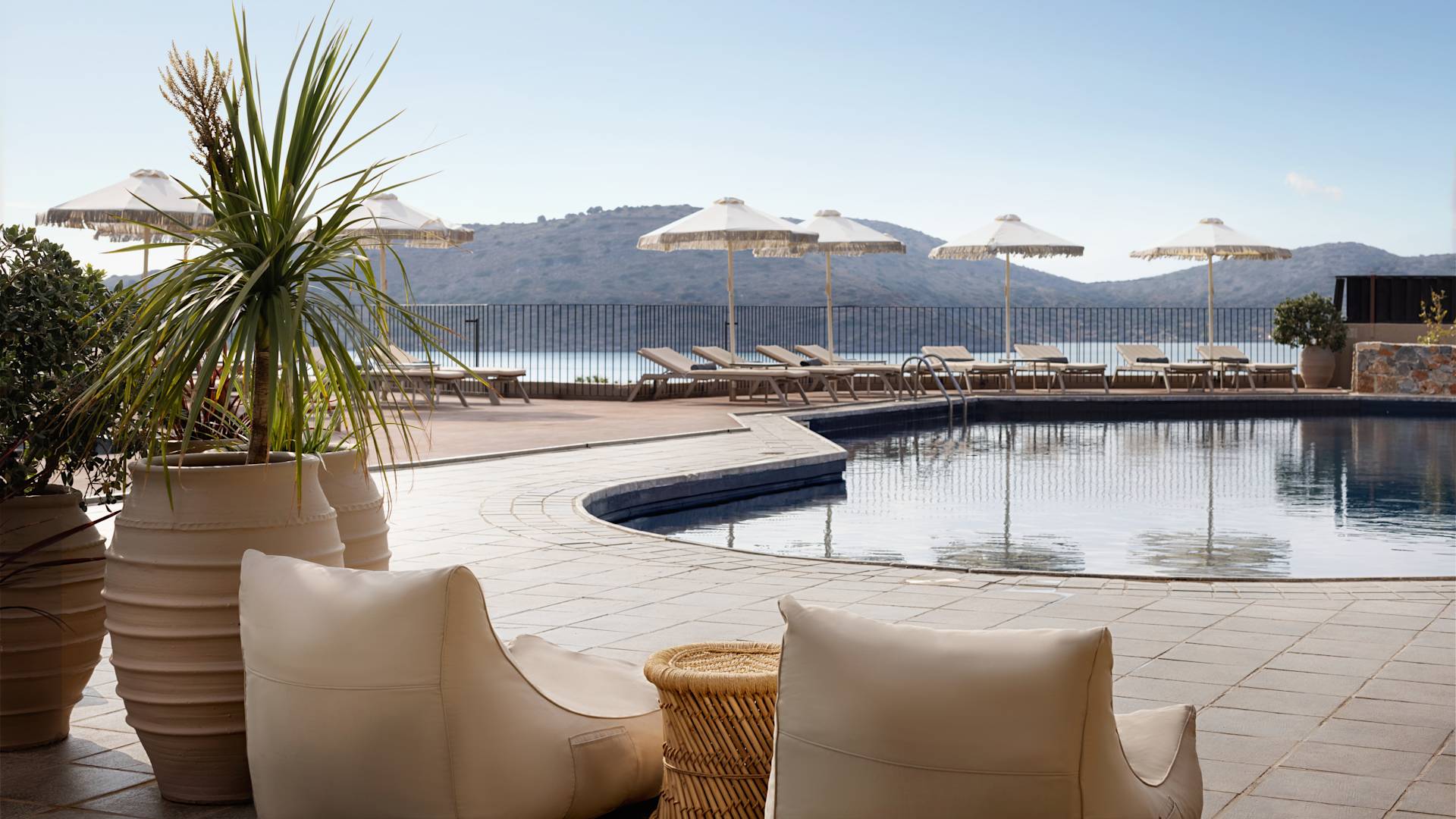 Venkovní bazén s lehátky a výhledem na hory a moře.