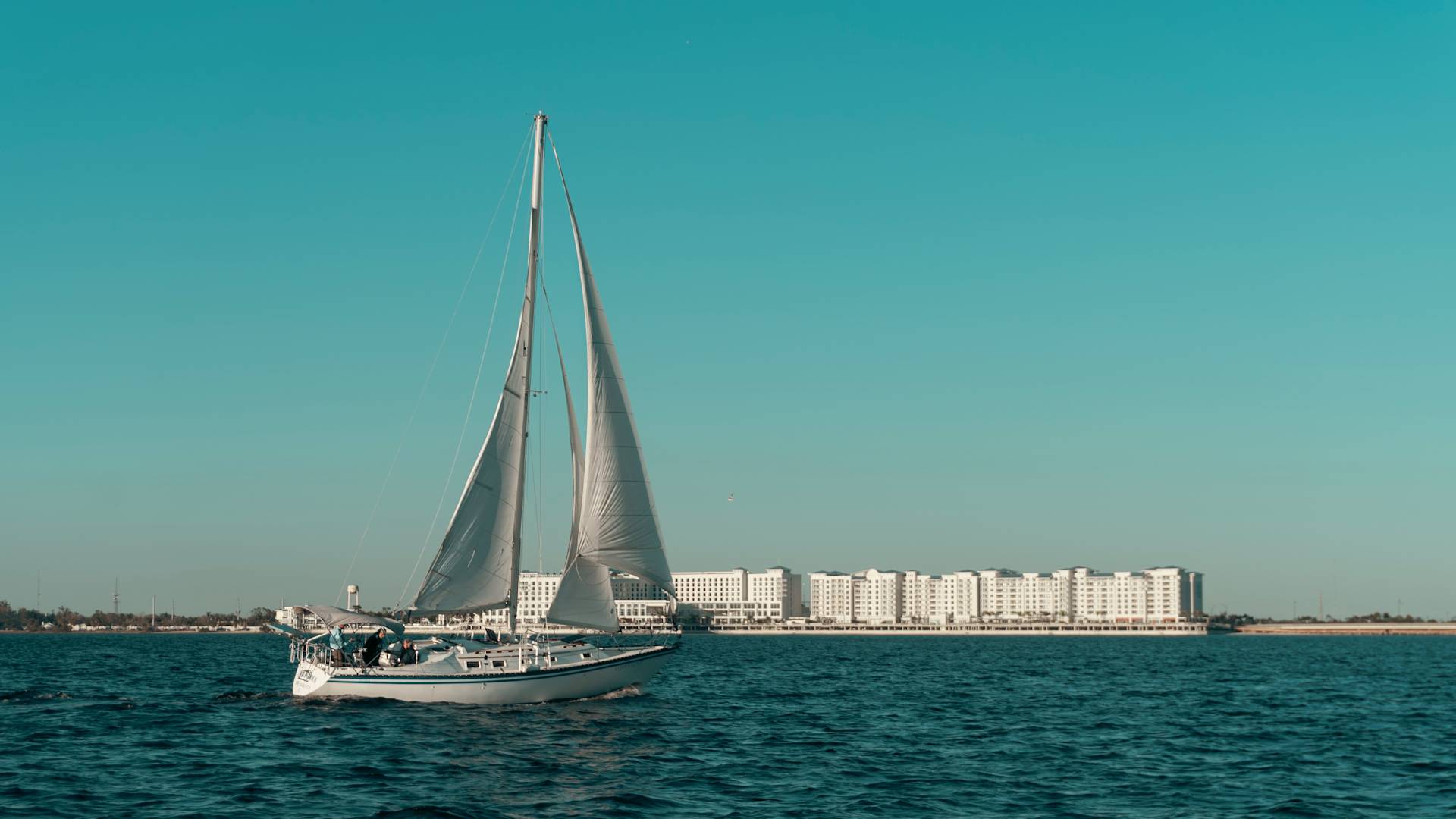 a Sail Boat on the Water with View of Hotel Exterior in Background