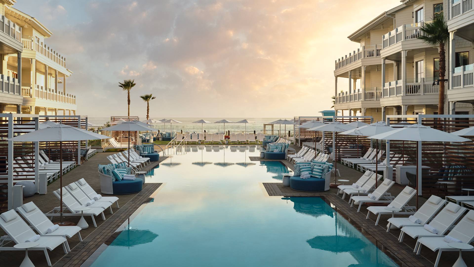 Vista da piscina e espreguiçadeiras voltadas para o mar ao pôr do sol